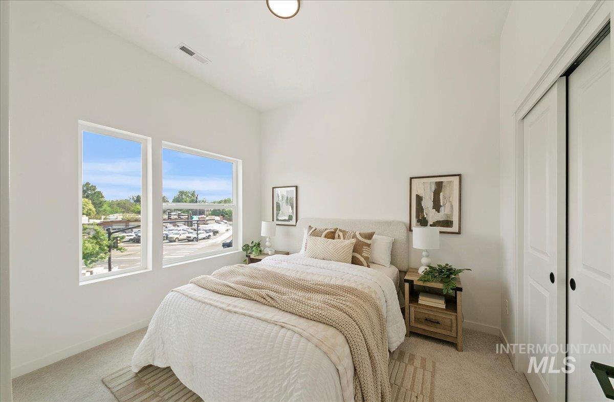 Bedroom with light colored carpet and a closet