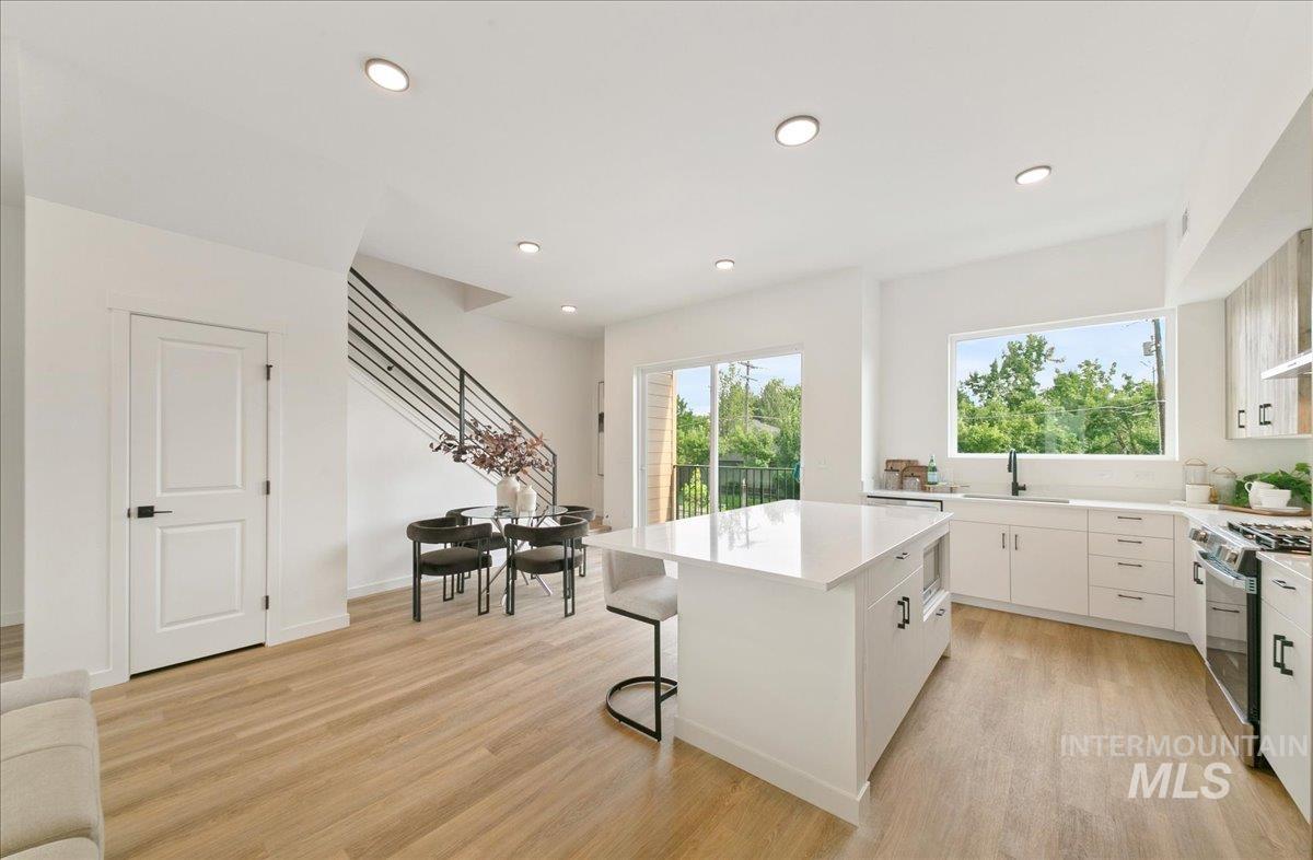 Kitchen featuring a center island, range with gas stovetop, light wood-style flooring, white cabinetry, and recessed lighting