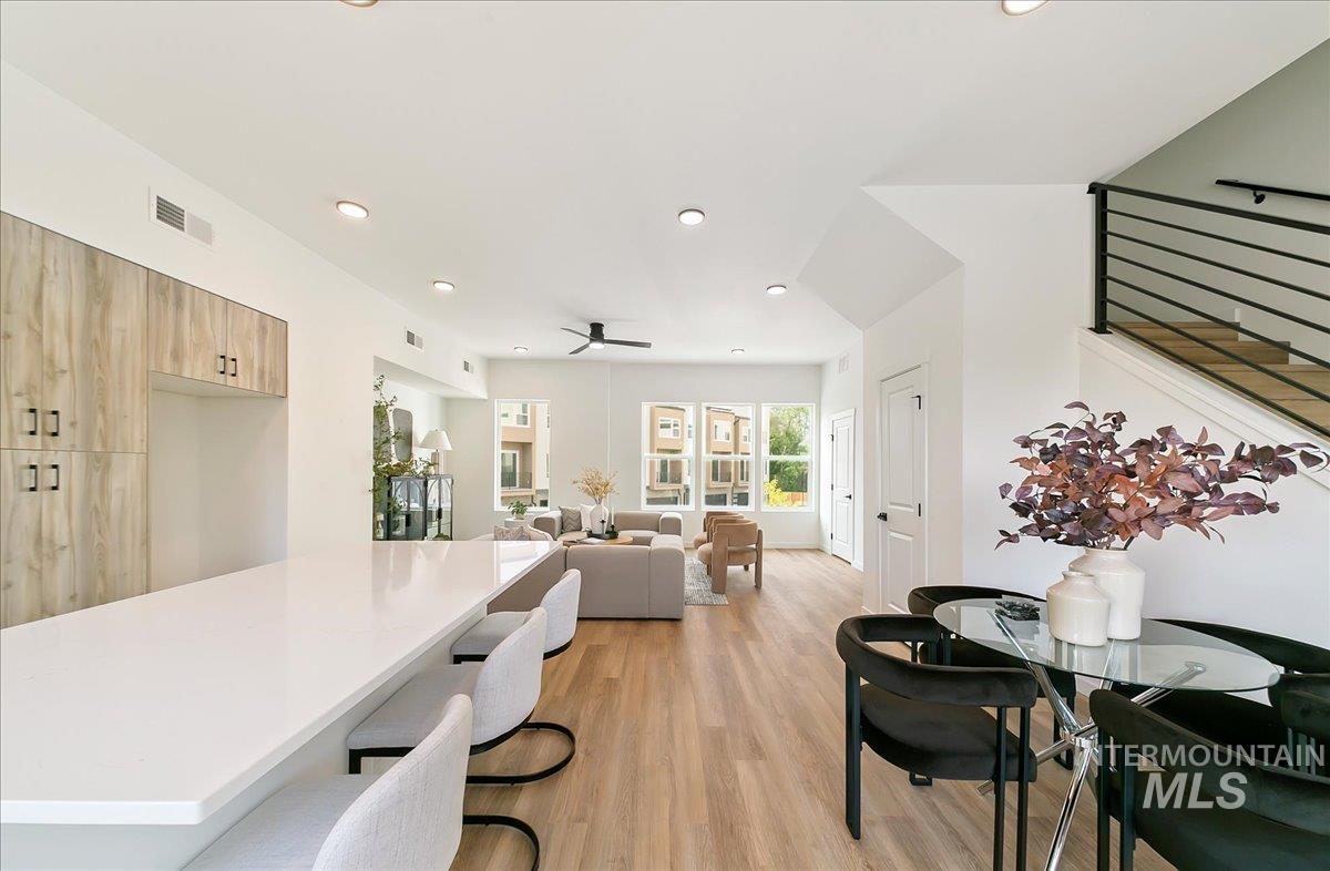 Dining area with light wood-type flooring, recessed lighting, ceiling fan, and stairs
