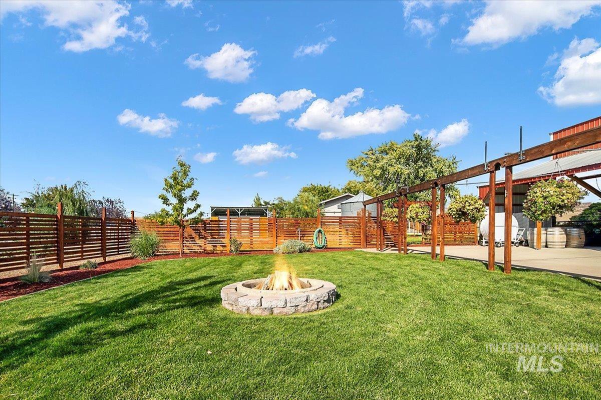 Fenced backyard featuring a fire pit and a pergola