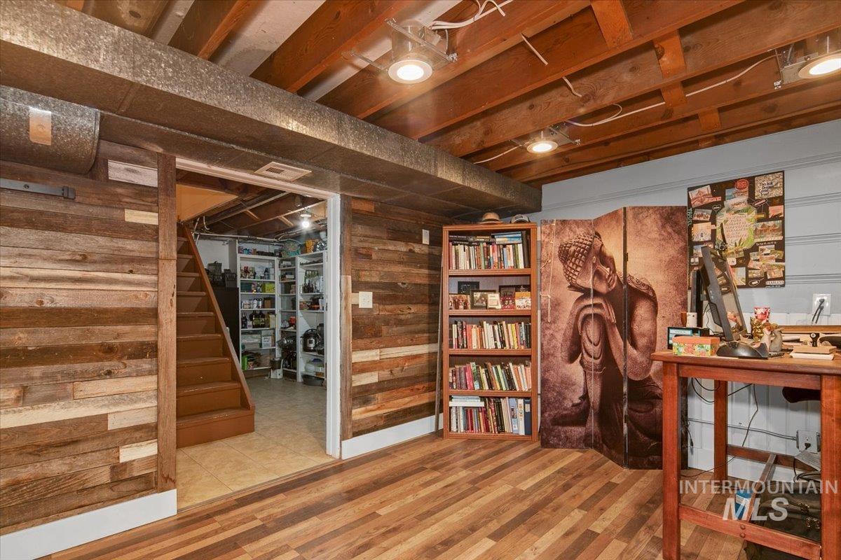 Basement with stairway, wooden walls, and wood finished floors