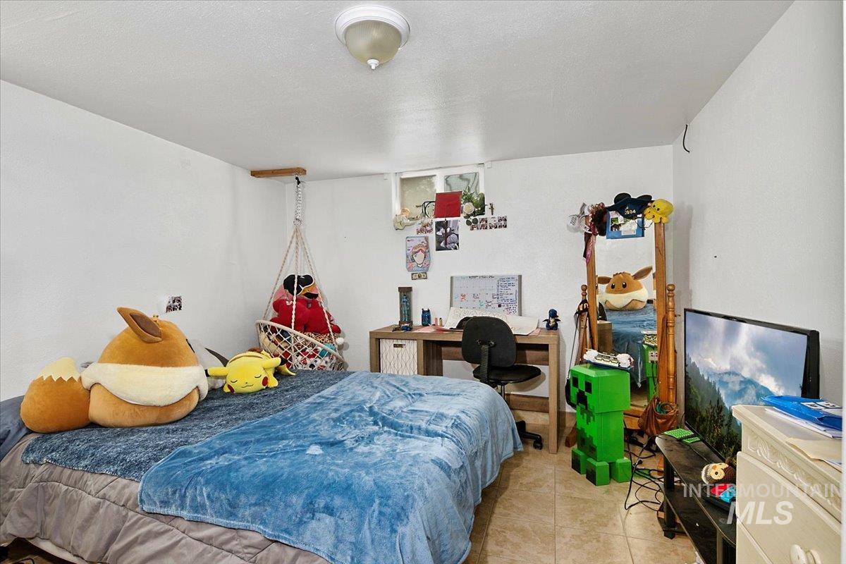 Bedroom with a desk, light tile patterned floors, and a textured ceiling