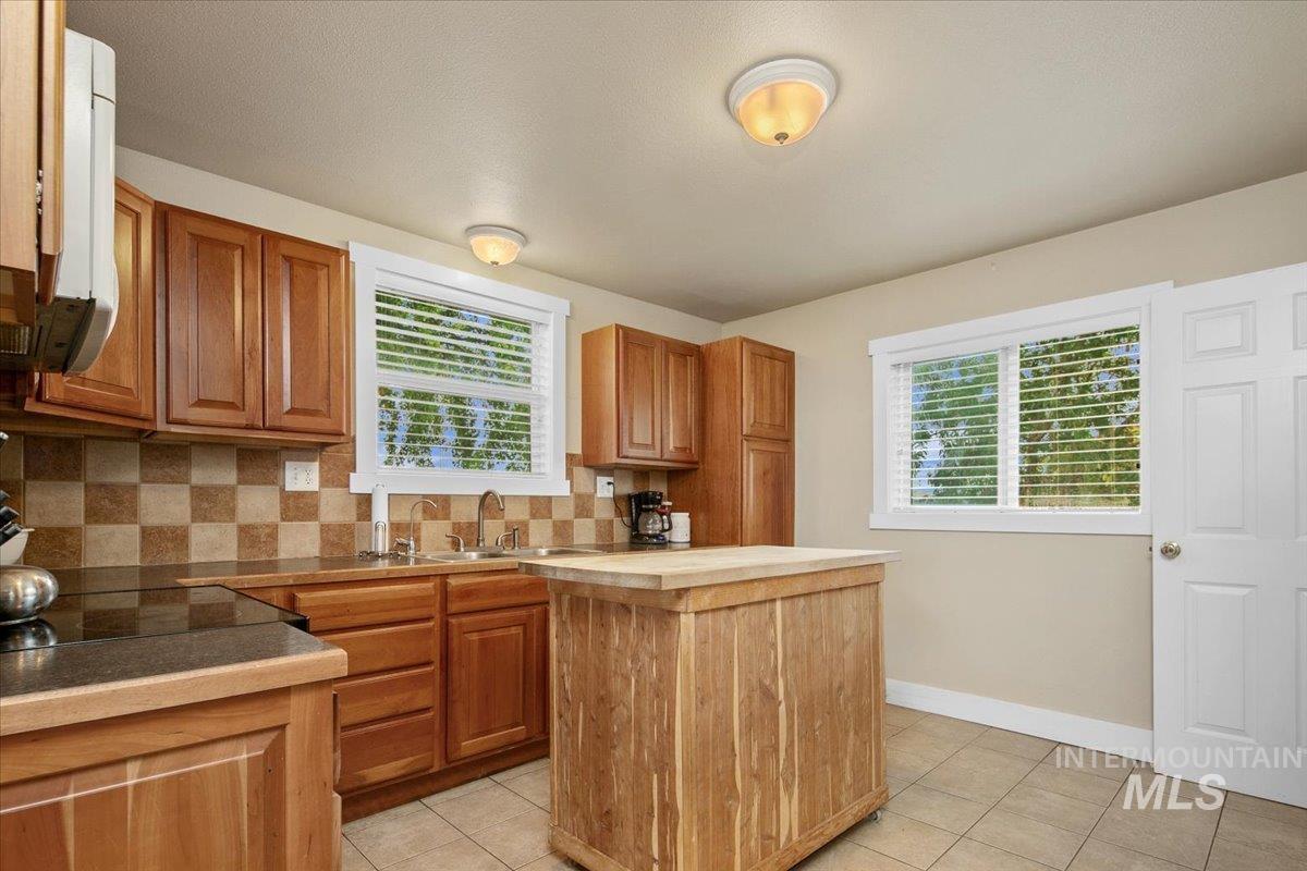 Kitchen featuring tasteful backsplash, brown cabinetry, a center island, and light tile patterned floors