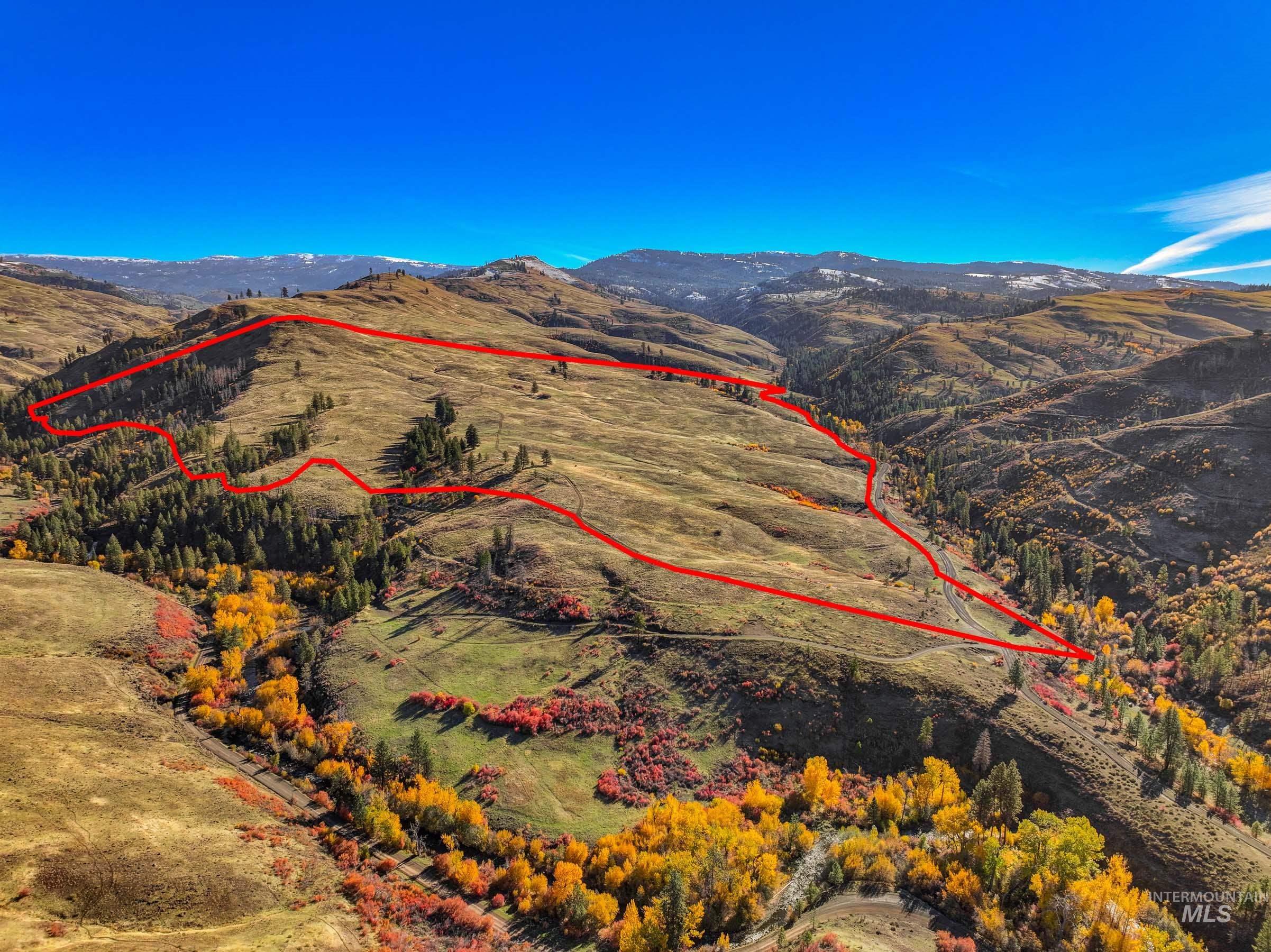 Aerial view of property's location with property parcel outlined and a mountainous background