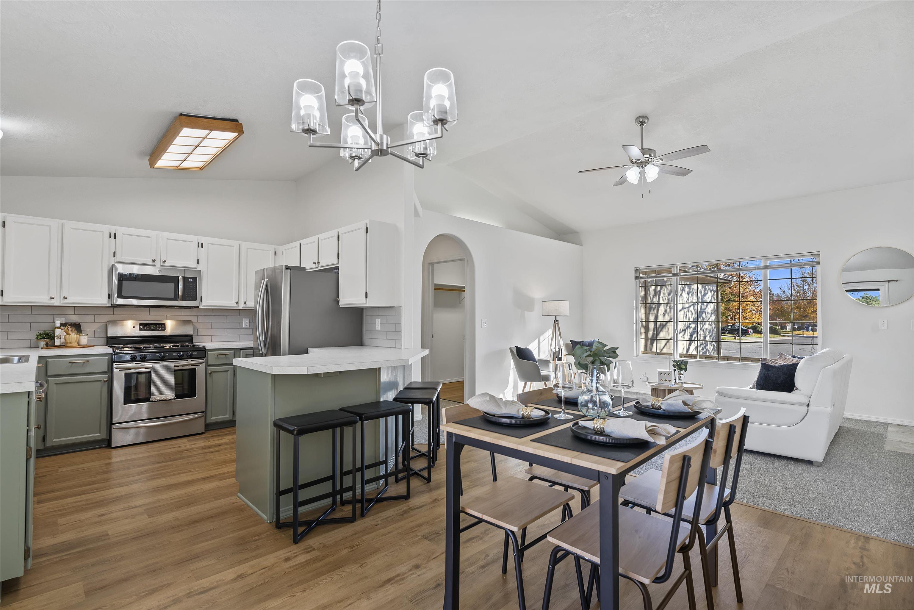 Dining space featuring arched walkways, lofted ceiling, light wood-style floors, ceiling fan, and a chandelier