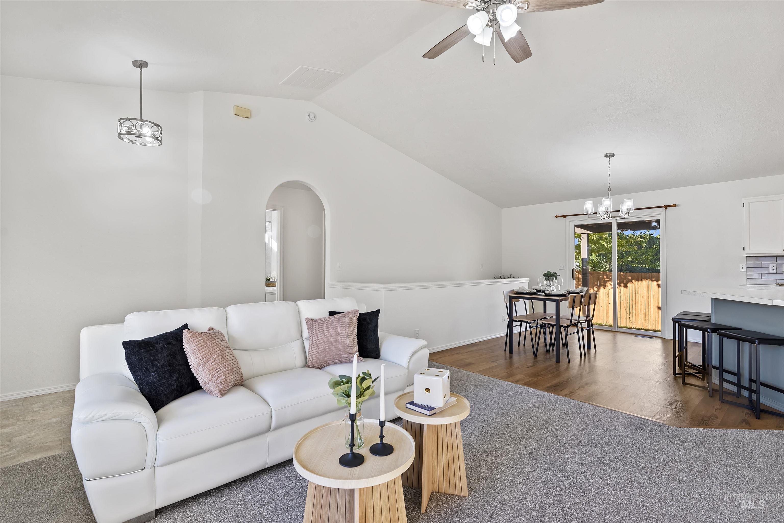 Living area with a chandelier, vaulted ceiling, arched walkways, a ceiling fan, and dark wood-type flooring