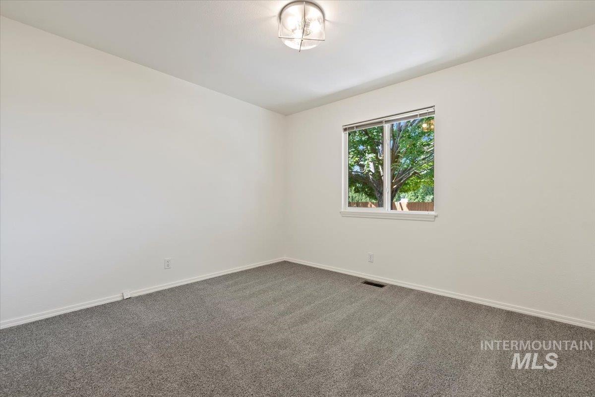 Empty room with baseboards and dark carpet