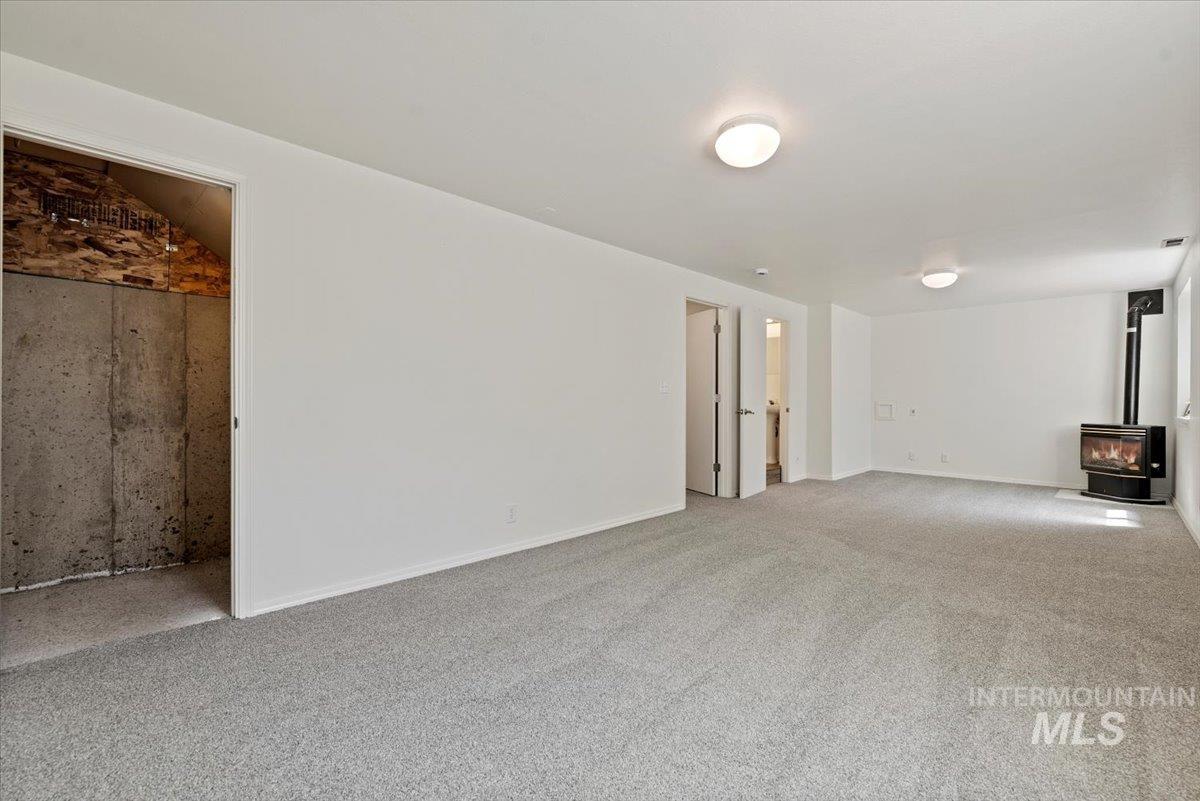 Basement Family room featuring a wood stove and carpet