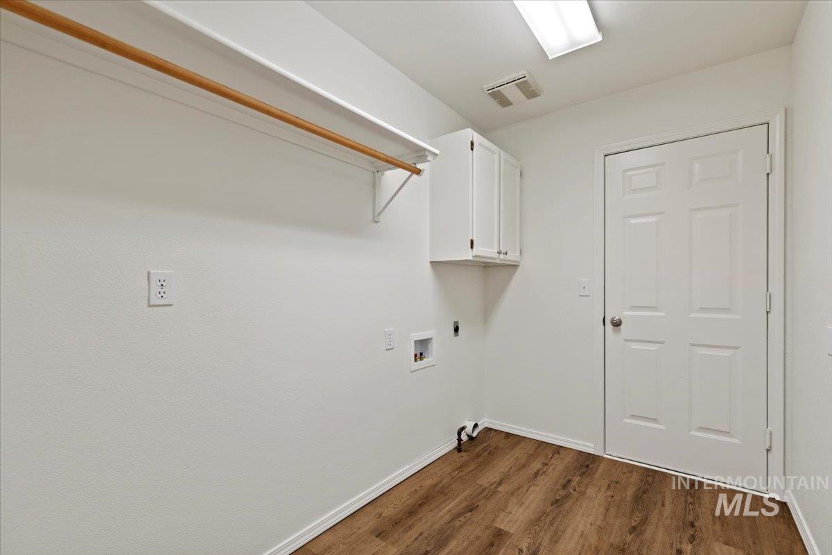 Washroom with cabinet space, dark wood finished floors, washer hookup, and electric dryer hookup
