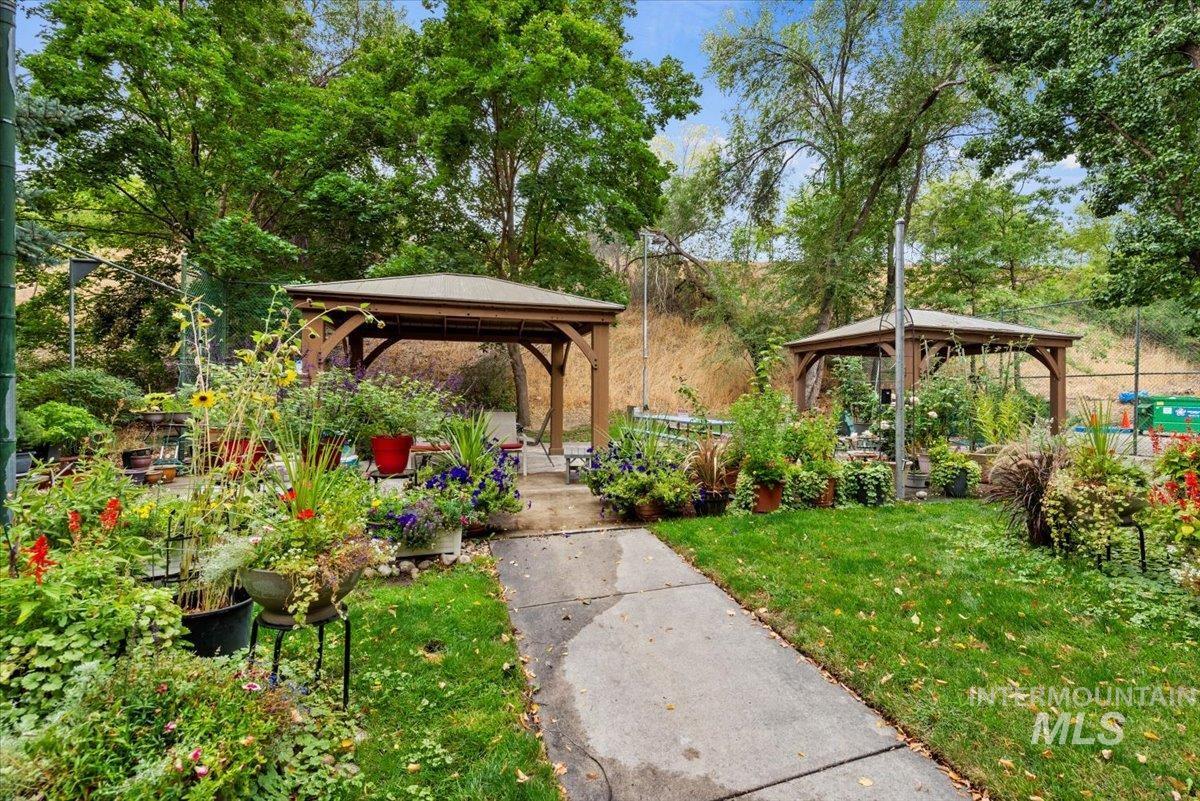 View of grassy yard with a gazebo, a patio area, and view of wooded area