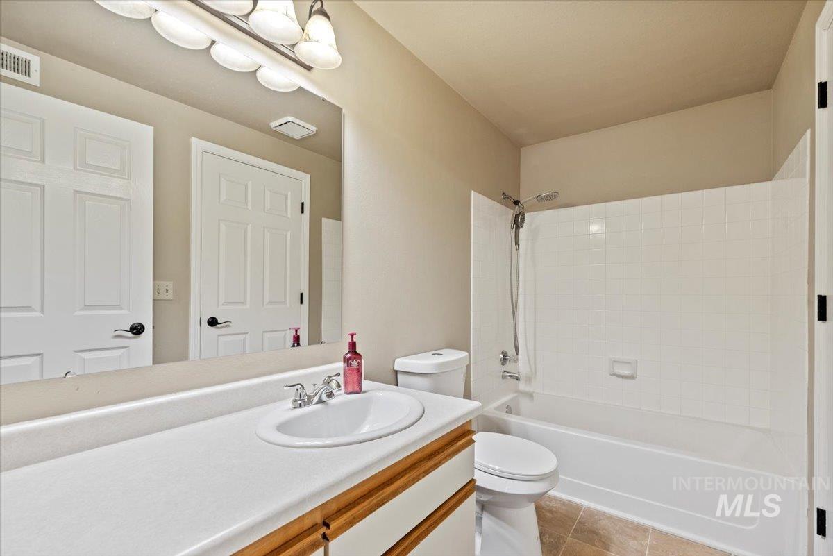 Bathroom featuring  shower combination, vanity, and light tile patterned flooring
