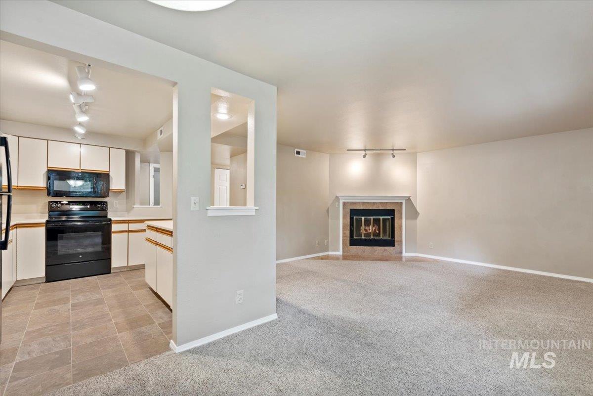 Unfurnished living room with track lighting, light carpet, and a fireplace