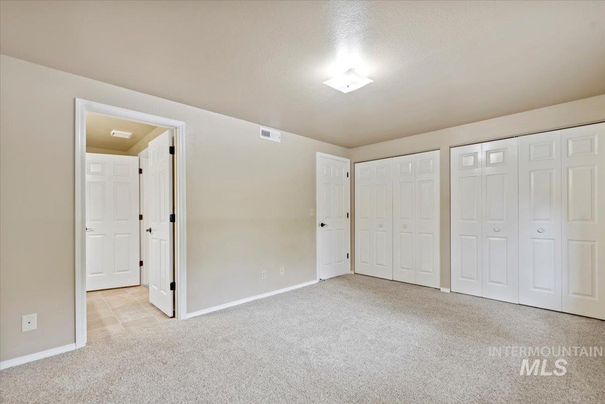 Unfurnished bedroom featuring two closets, light carpet, and a textured ceiling