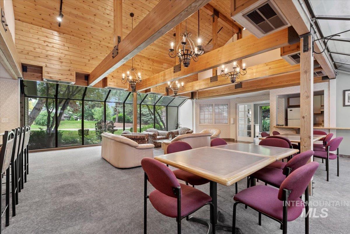 Dining area featuring carpet floors, floor to ceiling windows, and a wooden ceiling with exposed beams