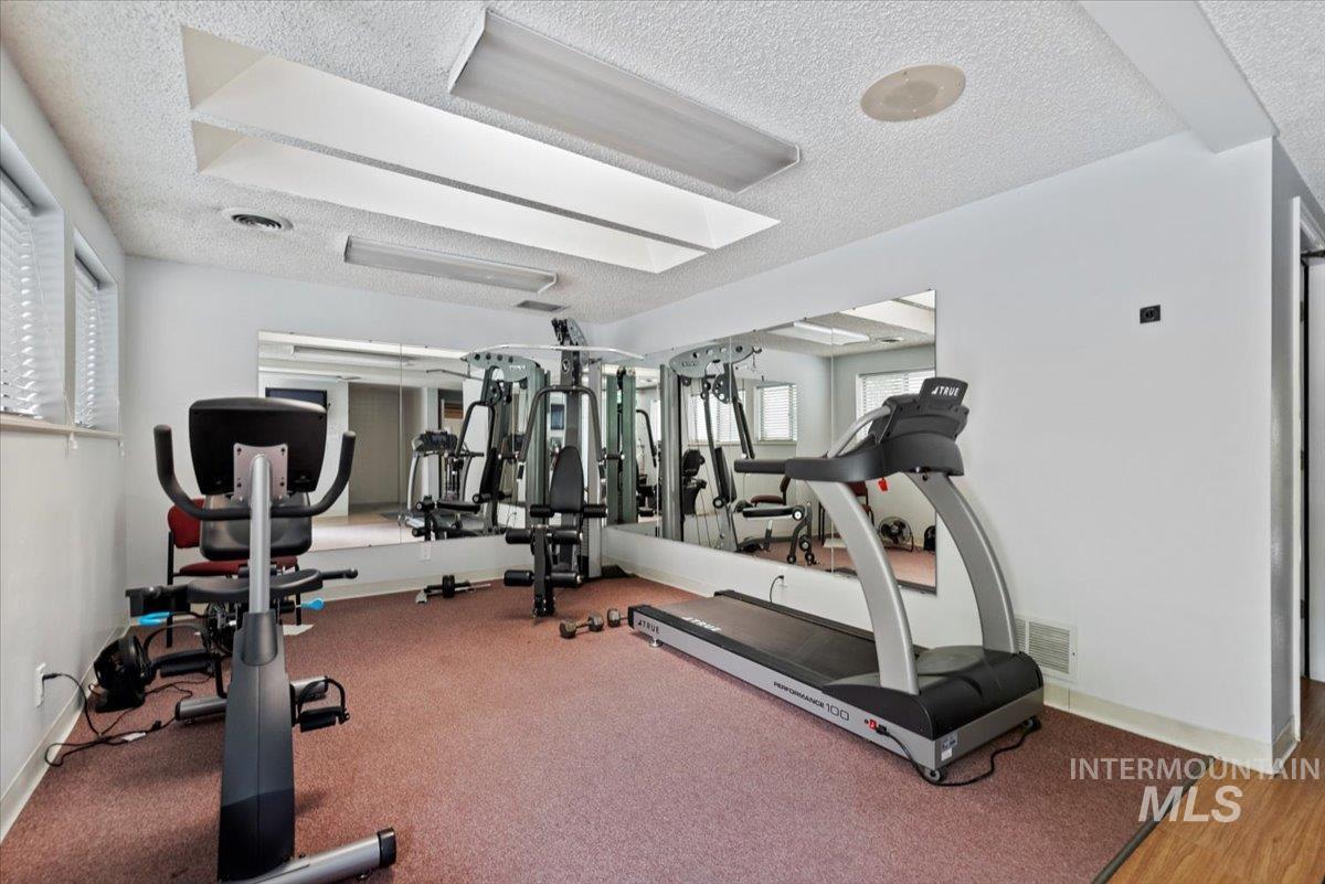 Exercise room with a textured ceiling and baseboards
