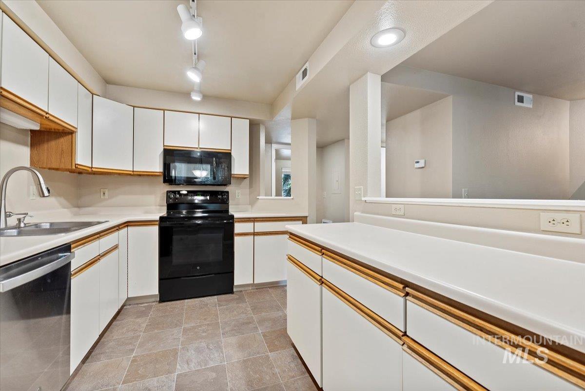 Kitchen featuring white cabinets, black appliances, light countertops, and recessed lighting