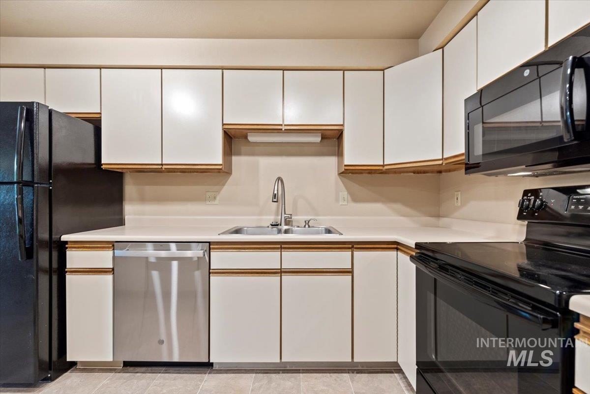 Kitchen featuring black appliances, white cabinets, light countertops, and light tile patterned floors