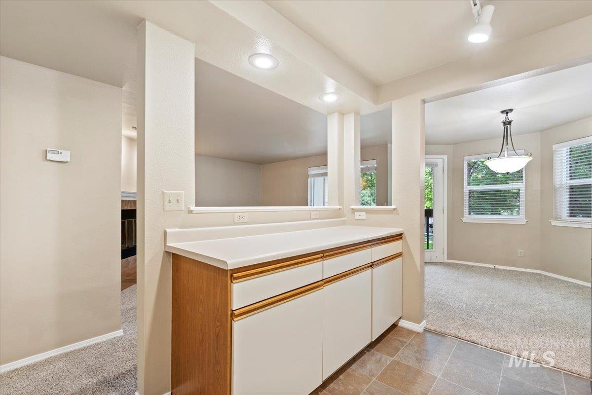Kitchen featuring light carpet, light countertops, brown cabinets, recessed lighting, and decorative light fixtures