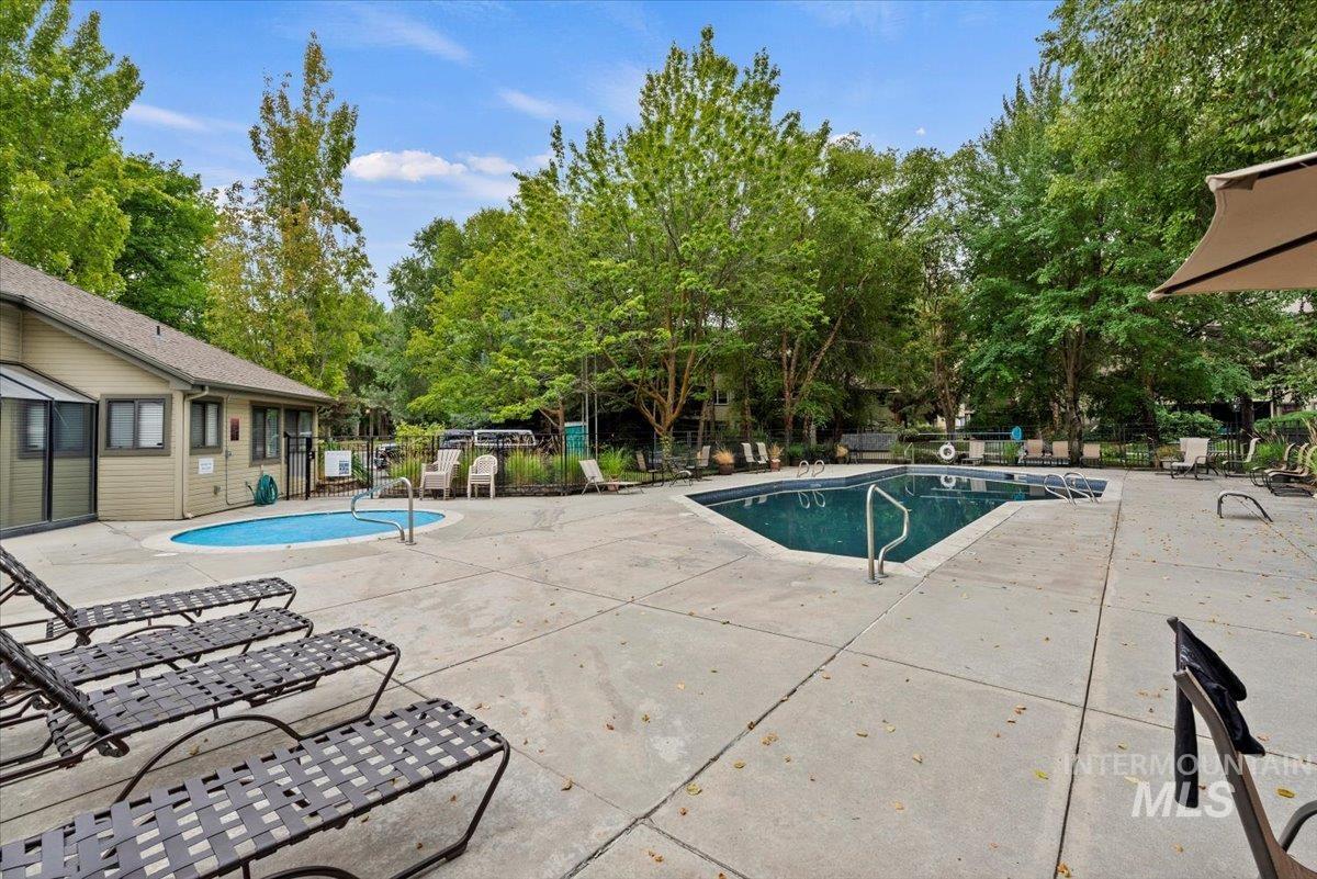 Community pool featuring a patio area and view of scattered trees
