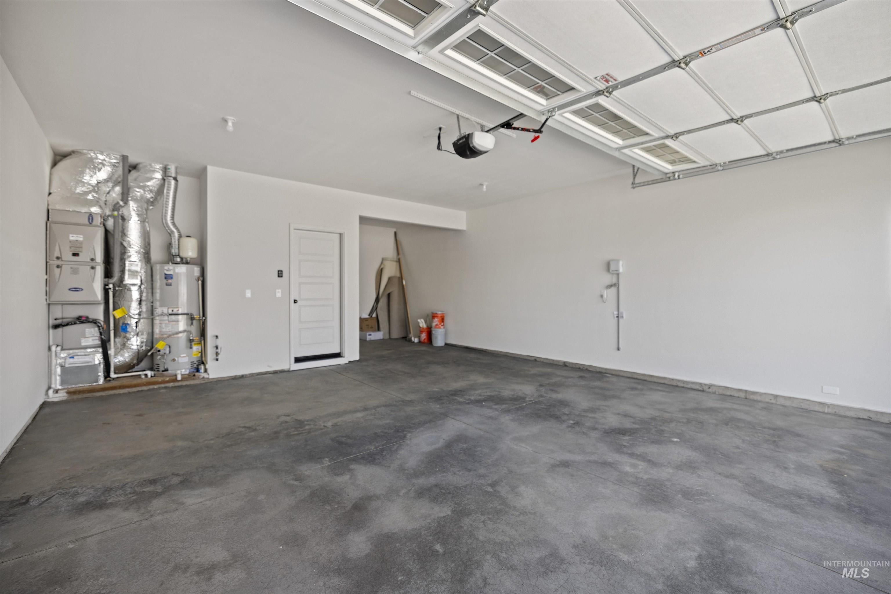 Garage featuring heating unit and strapped water heater
