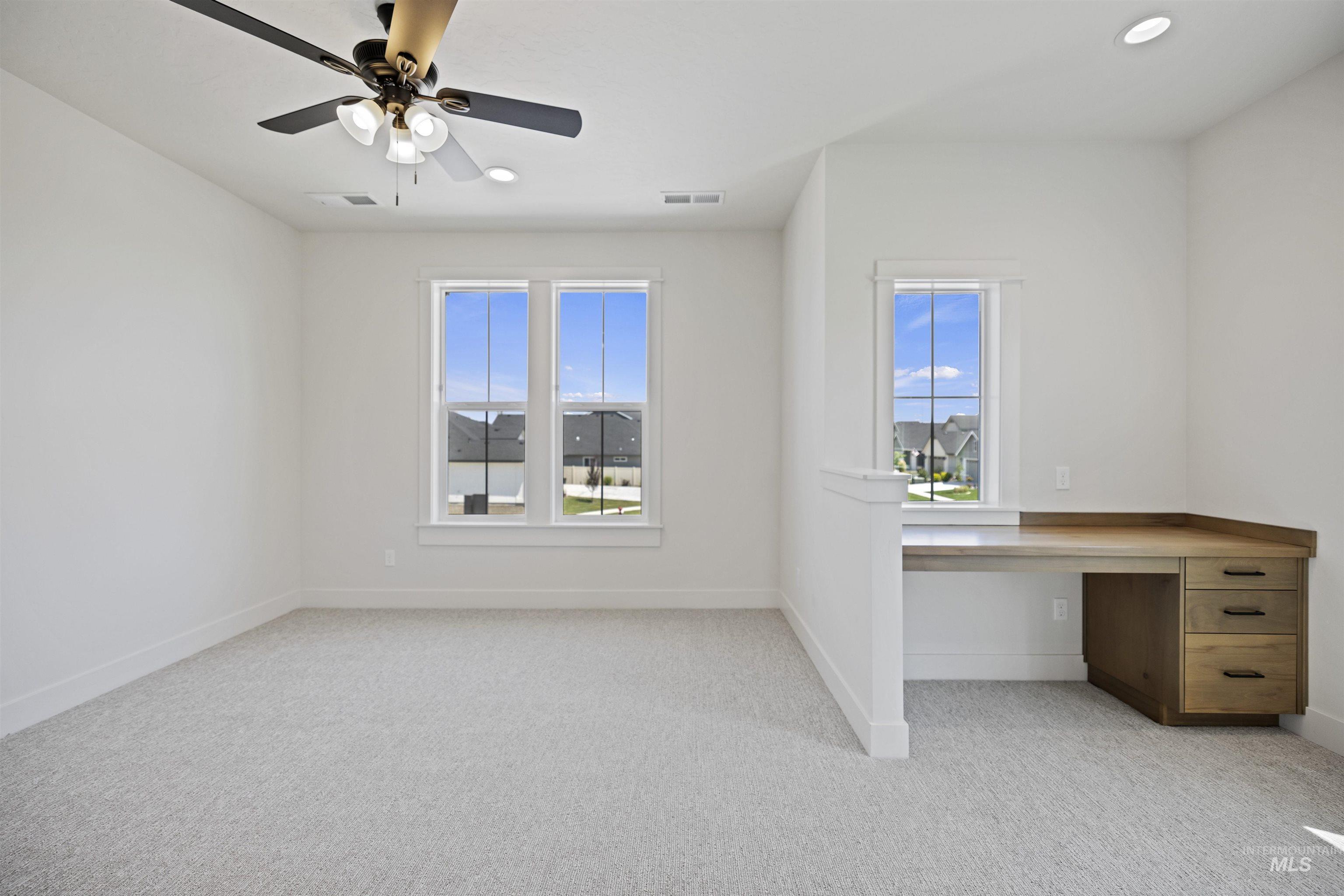 Unfurnished office with carpet, built in desk, a ceiling fan, and recessed lighting