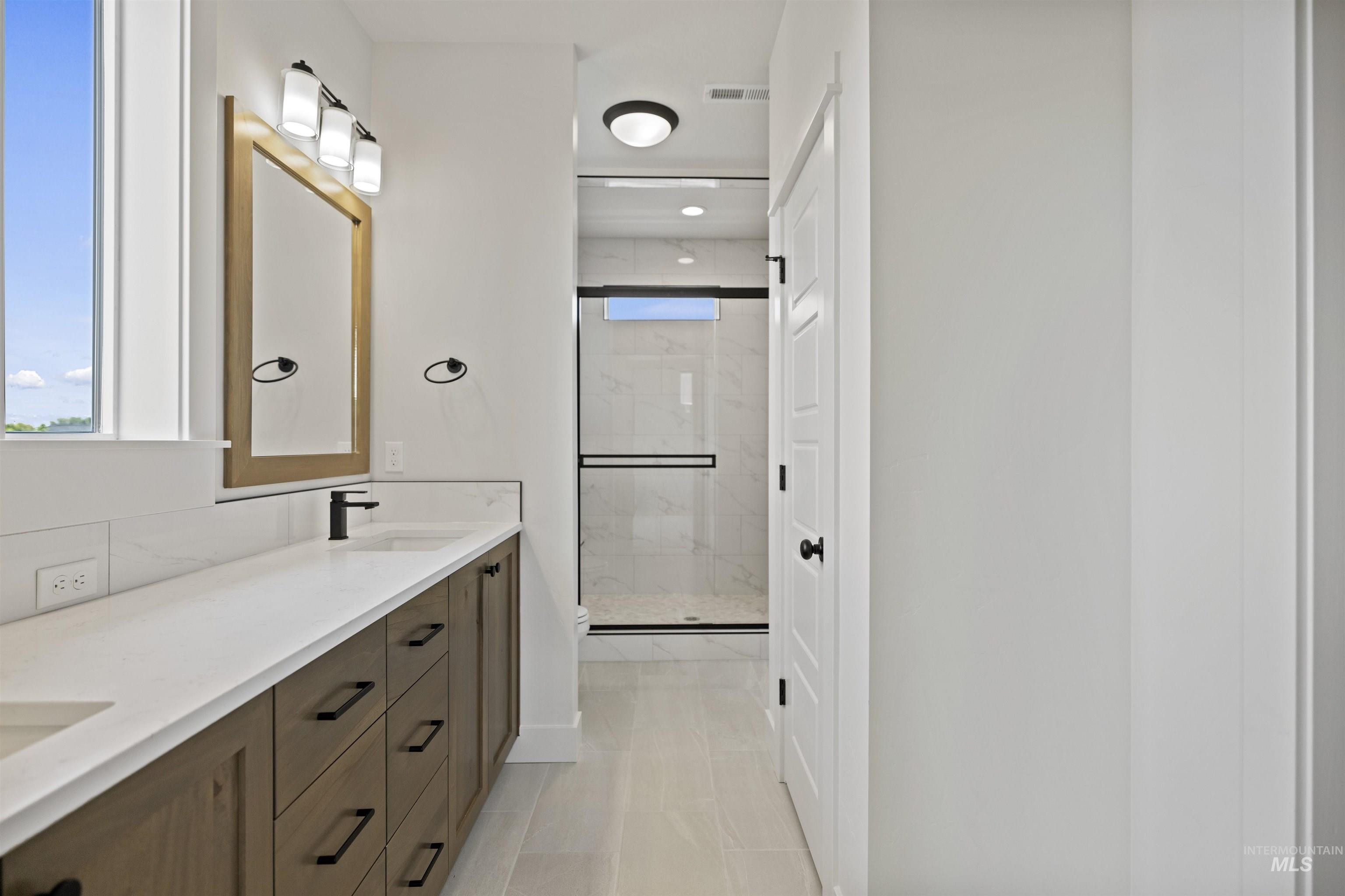 Bathroom with double vanity and a stall shower