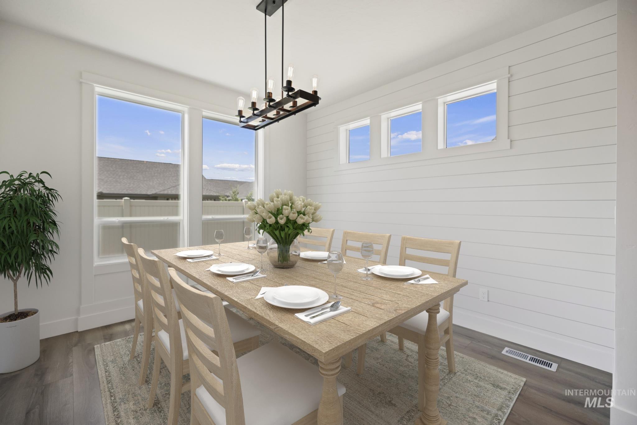 Dining room with a chandelier, wood finished floors, and wooden walls
