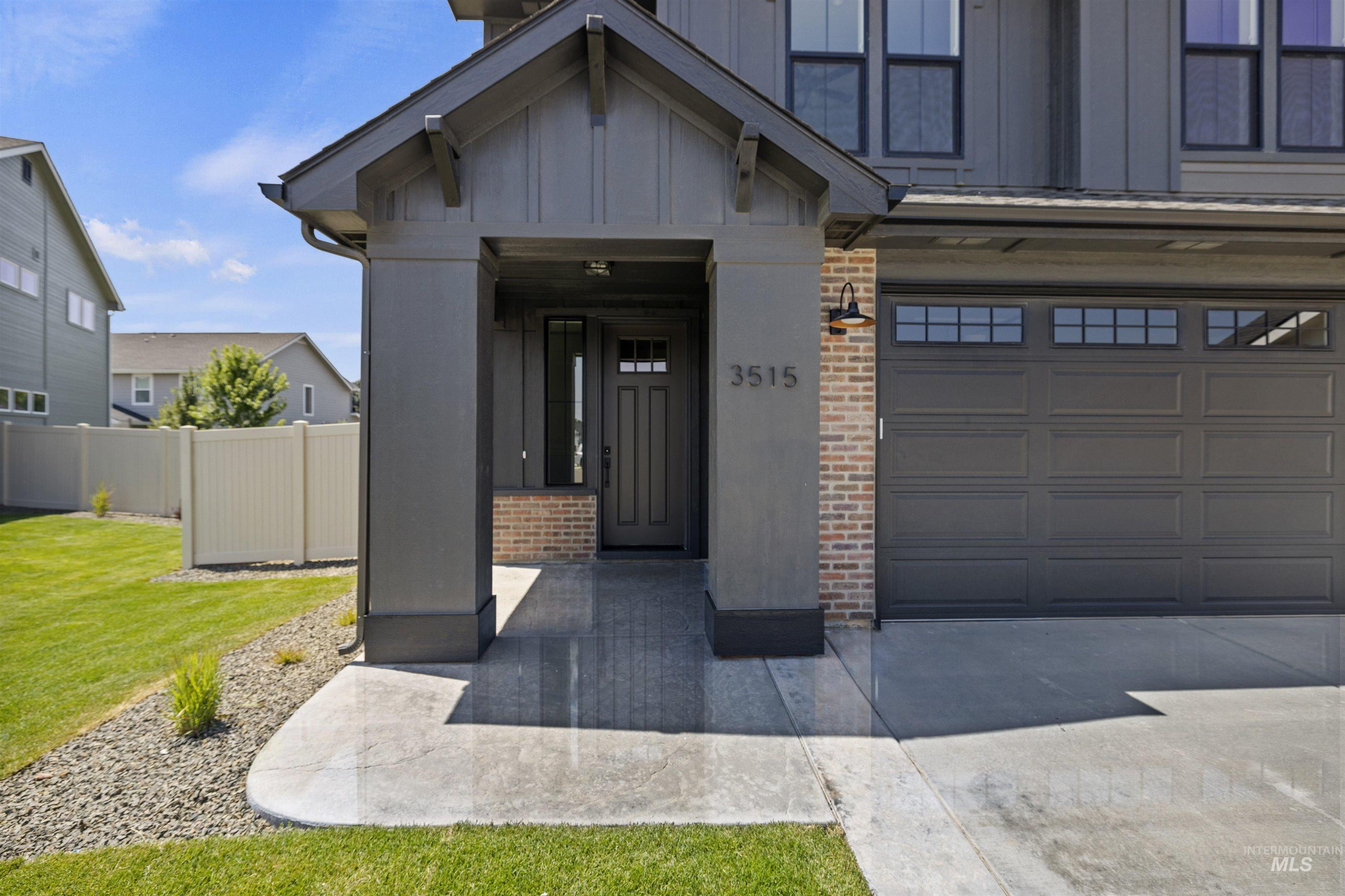 Entrance to property featuring brick siding, board and batten siding, driveway, and an attached garage