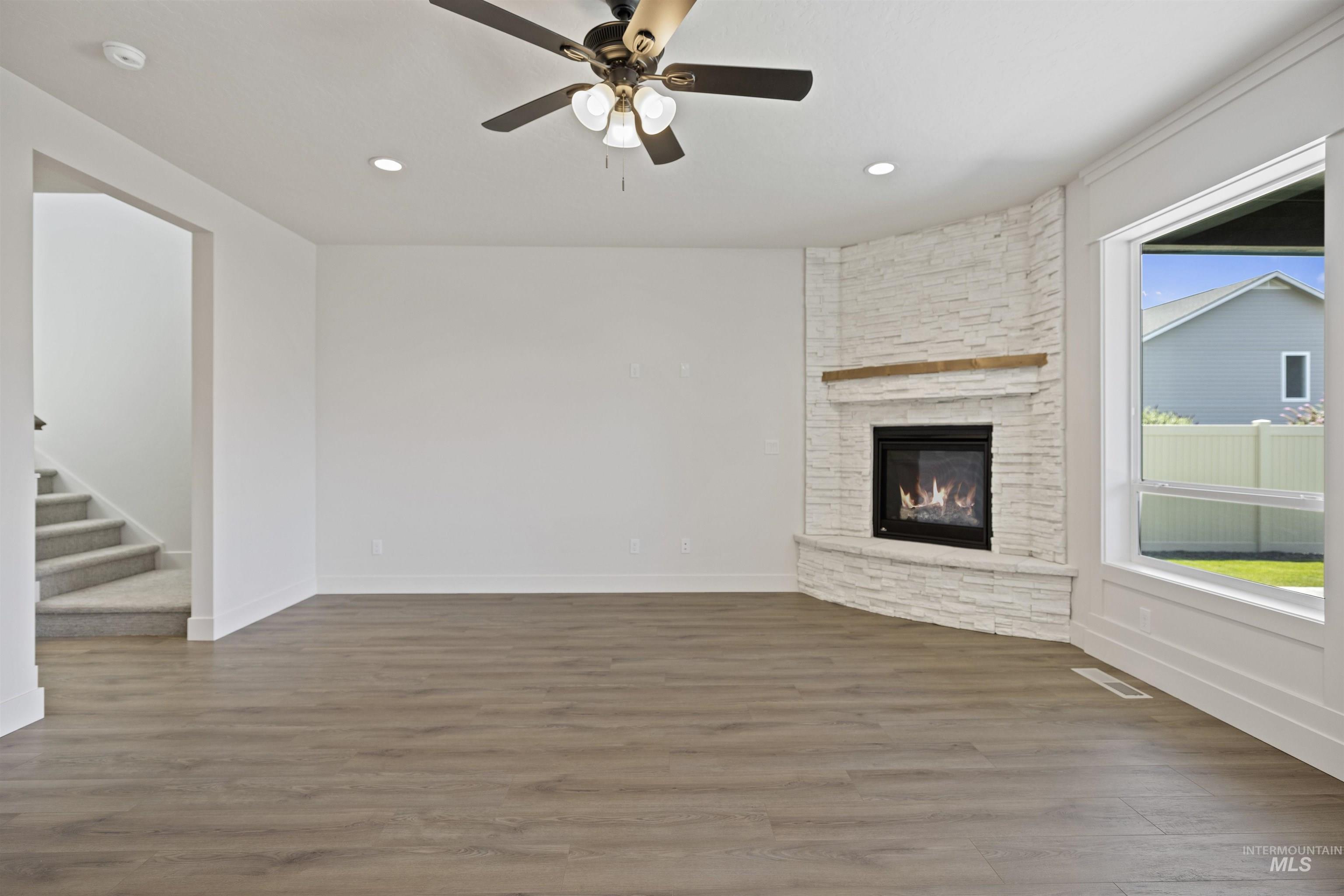 Unfurnished living room featuring wood finished floors, a fireplace, stairs, ceiling fan, and recessed lighting