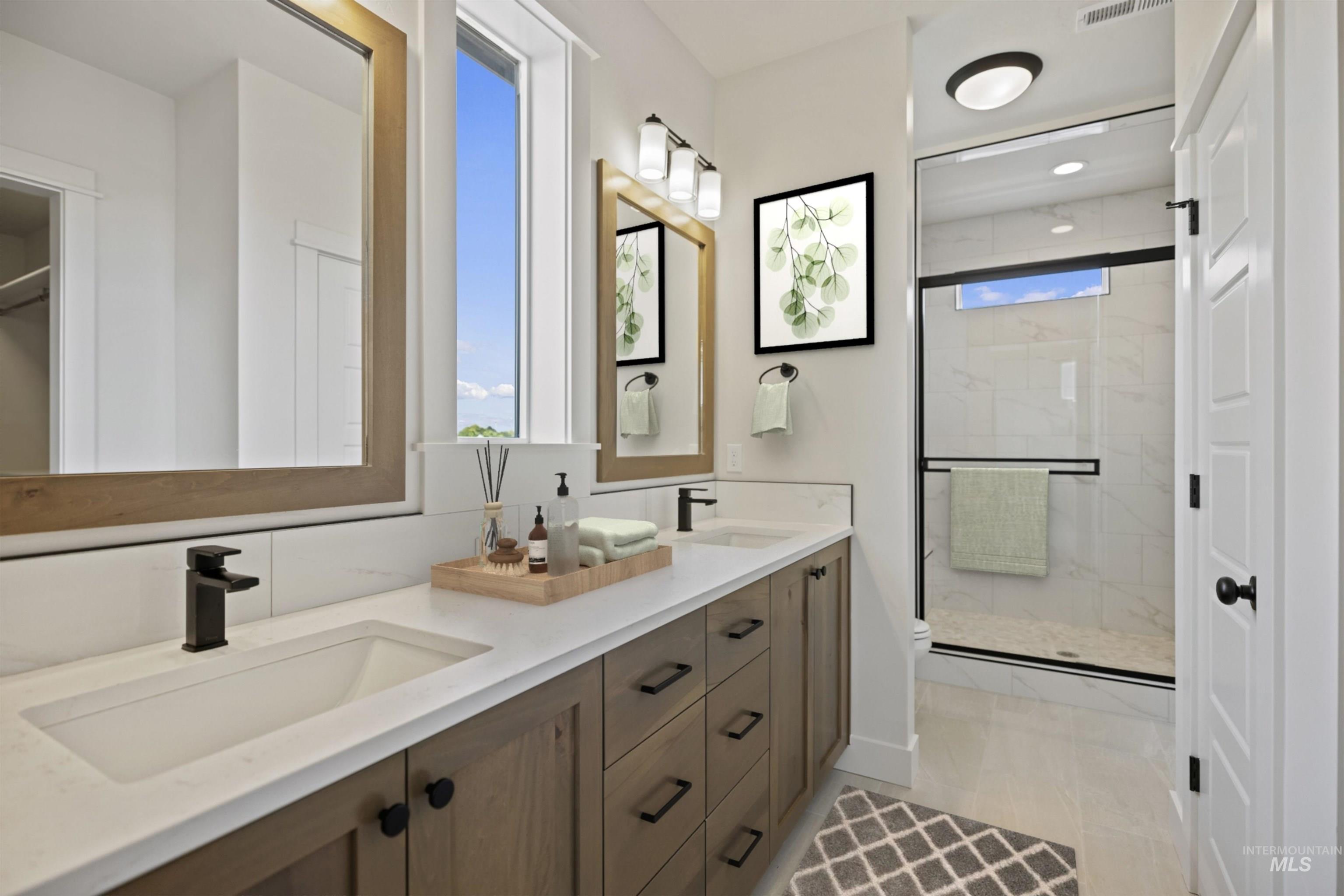Bathroom featuring plenty of natural light, a stall shower, and double vanity