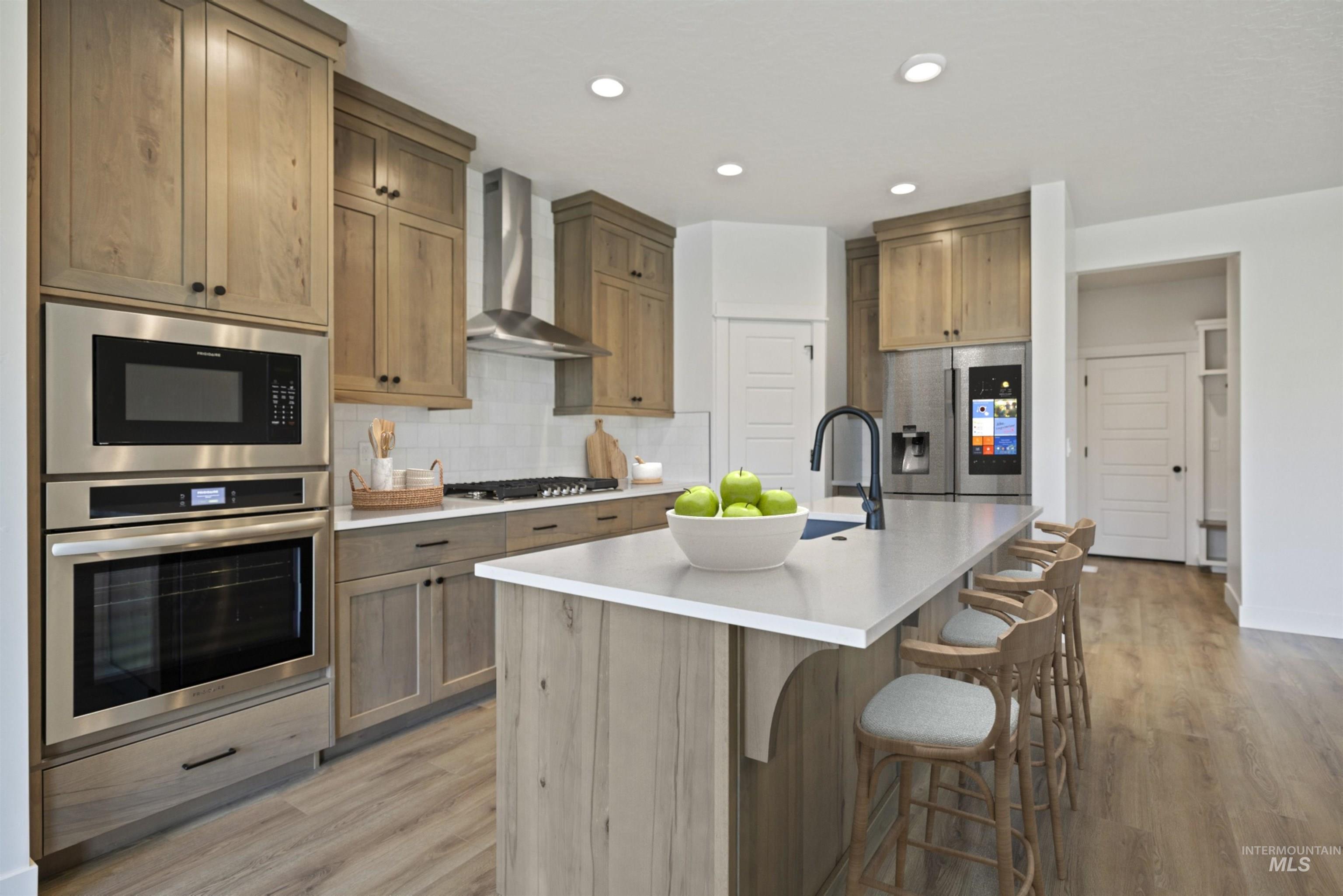 Kitchen with stainless steel appliances, light wood finished floors, a breakfast bar, decorative backsplash, and recessed lighting