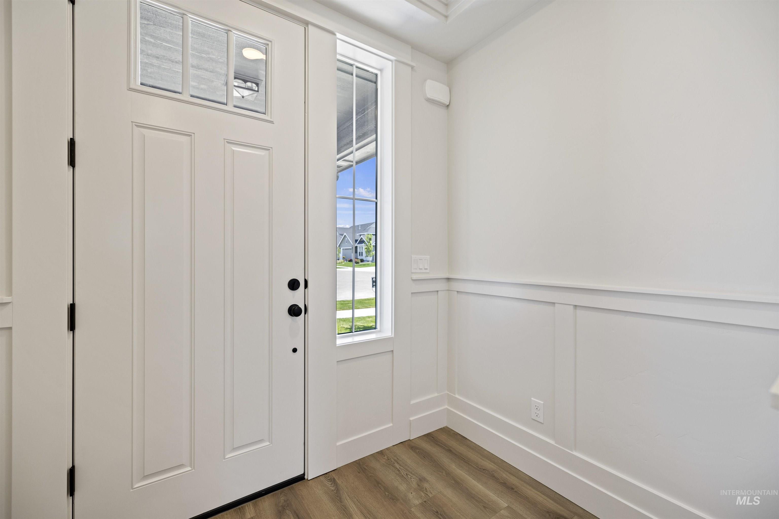 Foyer featuring wood finished floors, a decorative wall, and wainscoting
