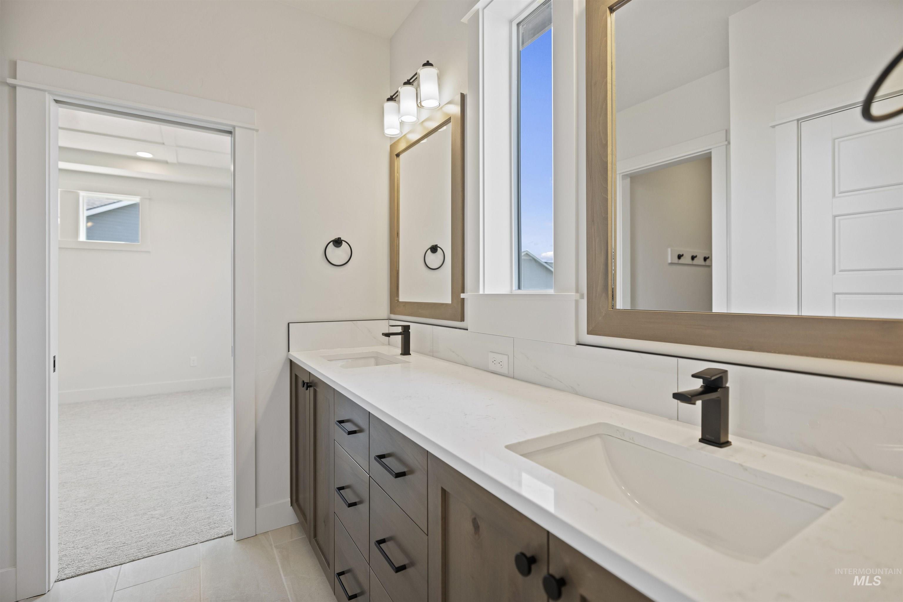 Bathroom featuring double vanity, healthy amount of natural light, and tile patterned flooring