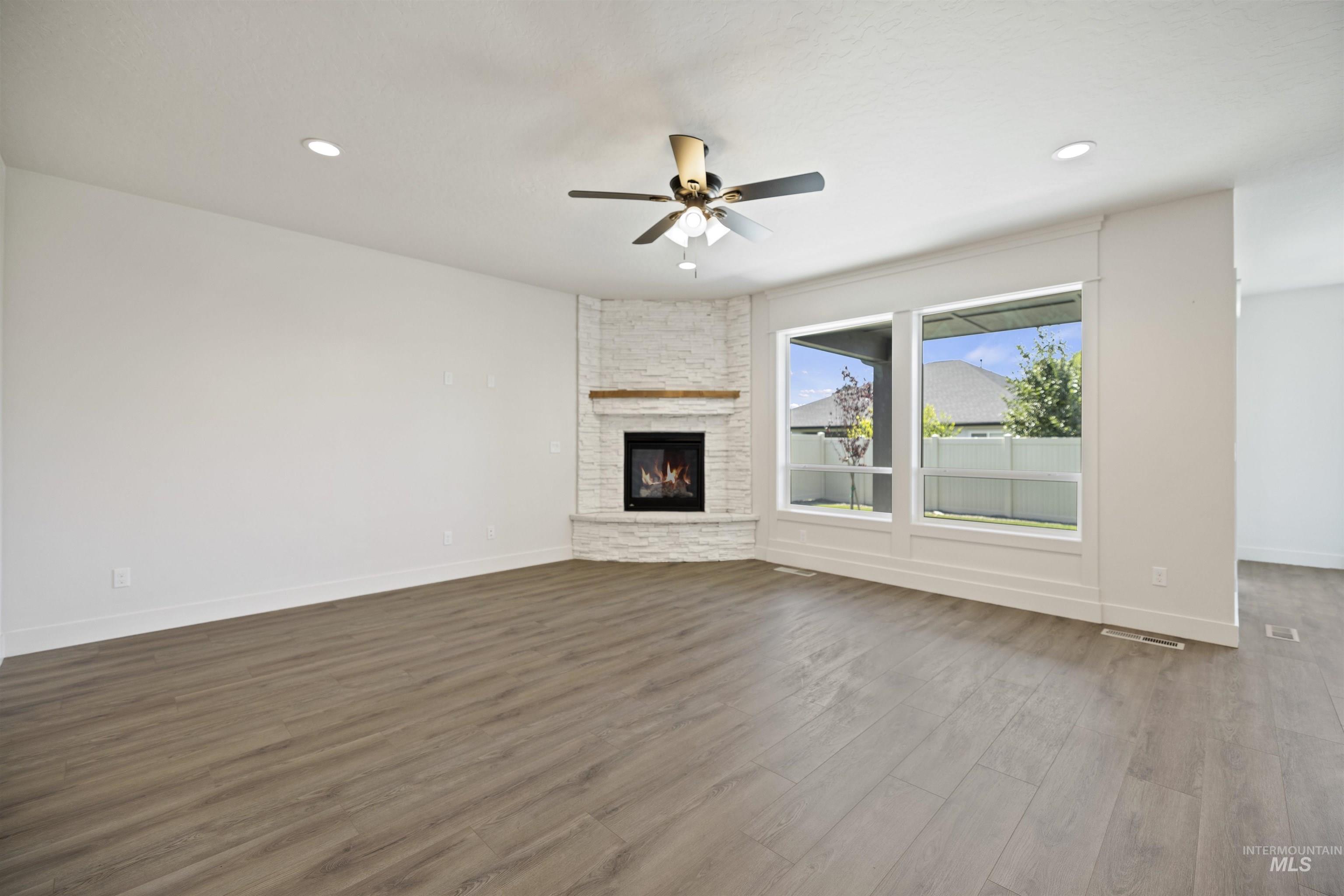 Unfurnished living room with ceiling fan, dark wood-style floors, a fireplace, and recessed lighting