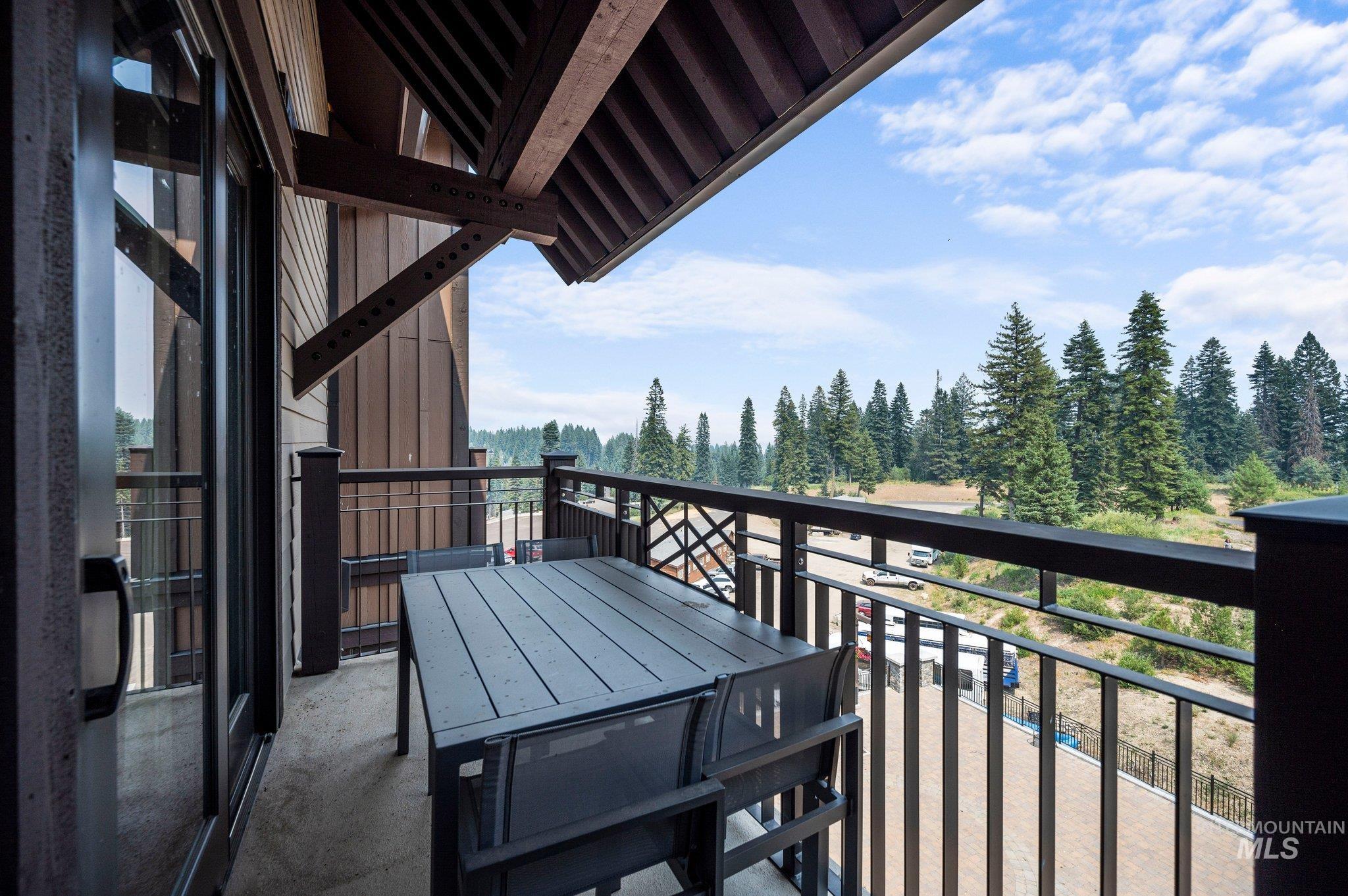 Balcony featuring view of wooded area and outdoor dining space