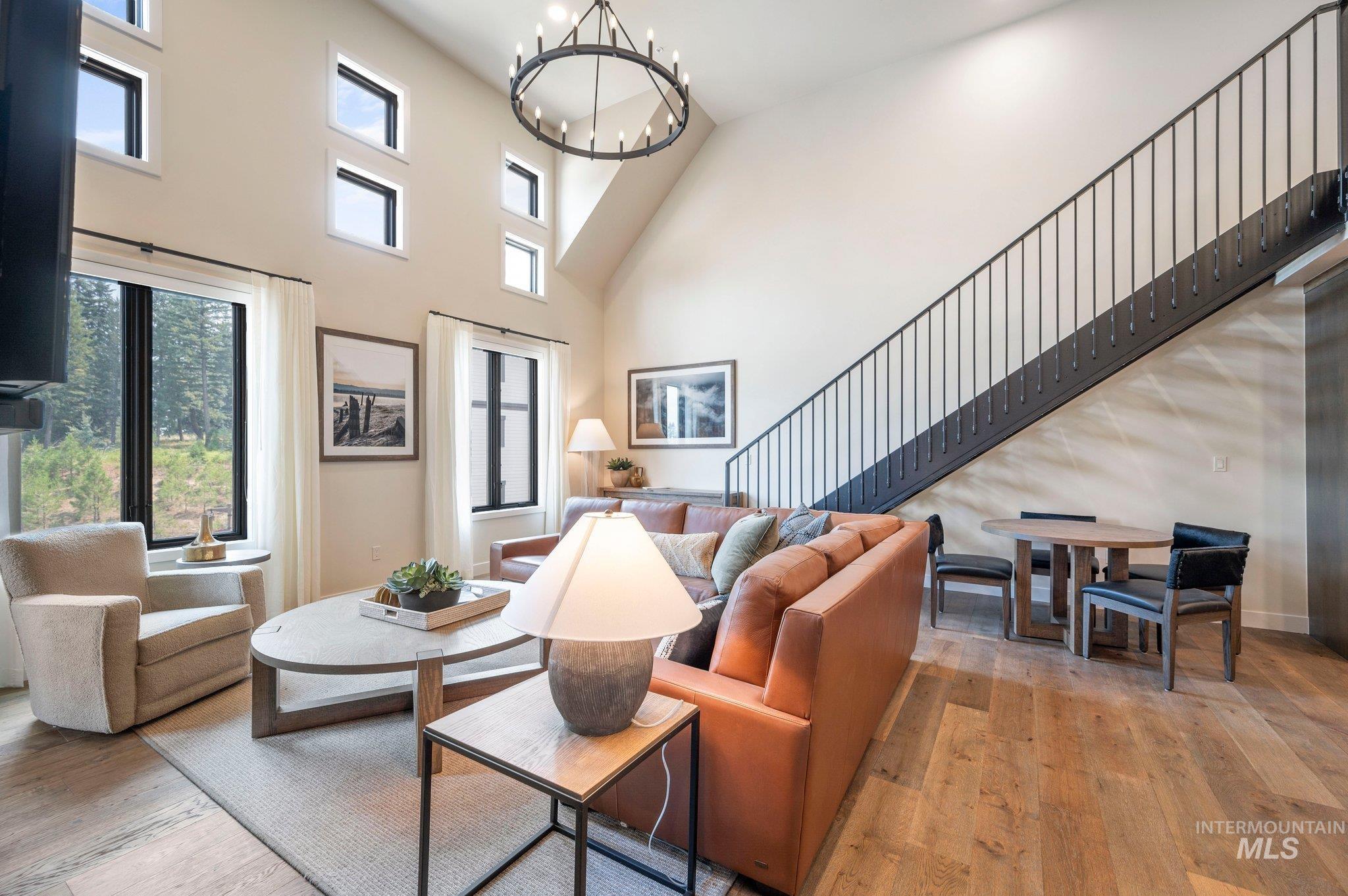 Living area with light wood-style floors, a towering ceiling, healthy amount of natural light, and a chandelier