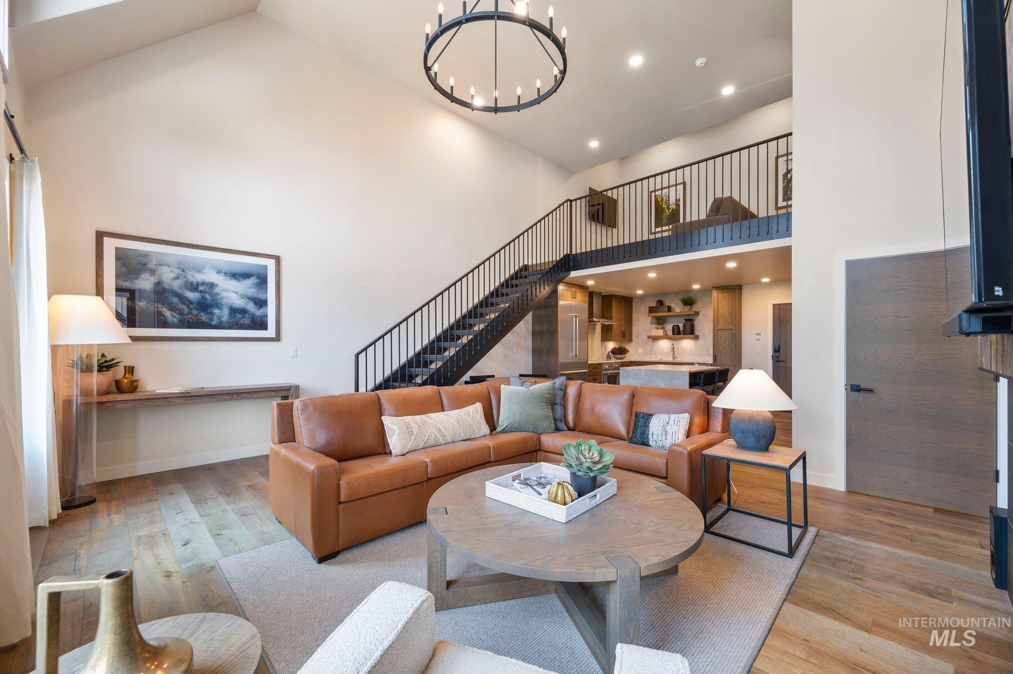 Living area featuring recessed lighting, hardwood / wood-style flooring, high vaulted ceiling, stairway, and a chandelier