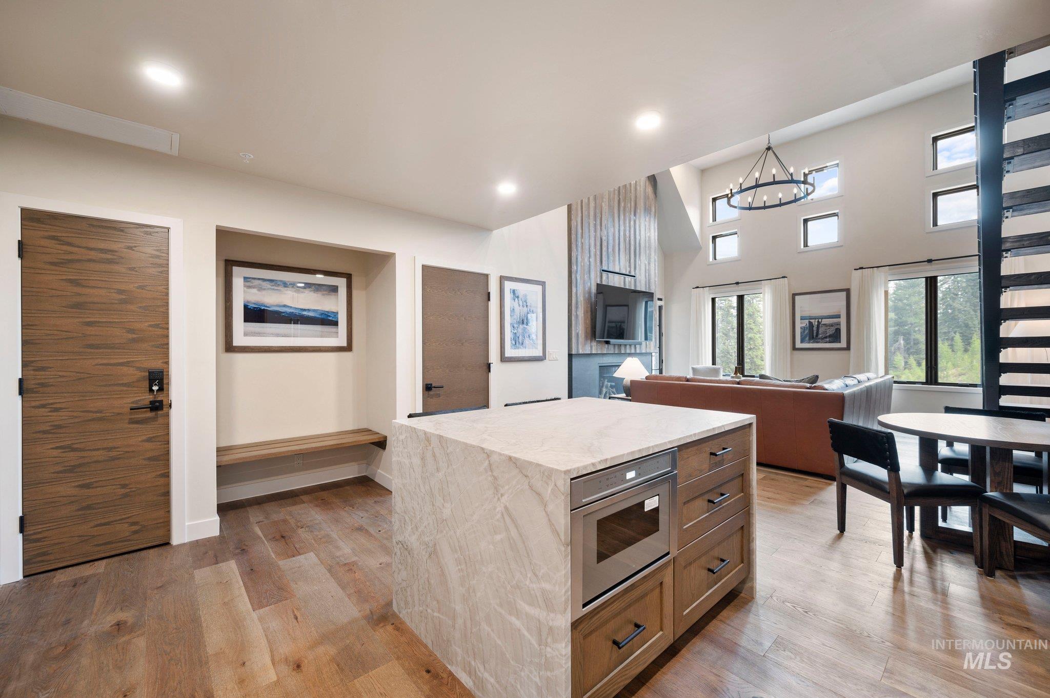 Kitchen featuring light stone countertops, light wood-style flooring, open floor plan, a towering ceiling, and recessed lighting