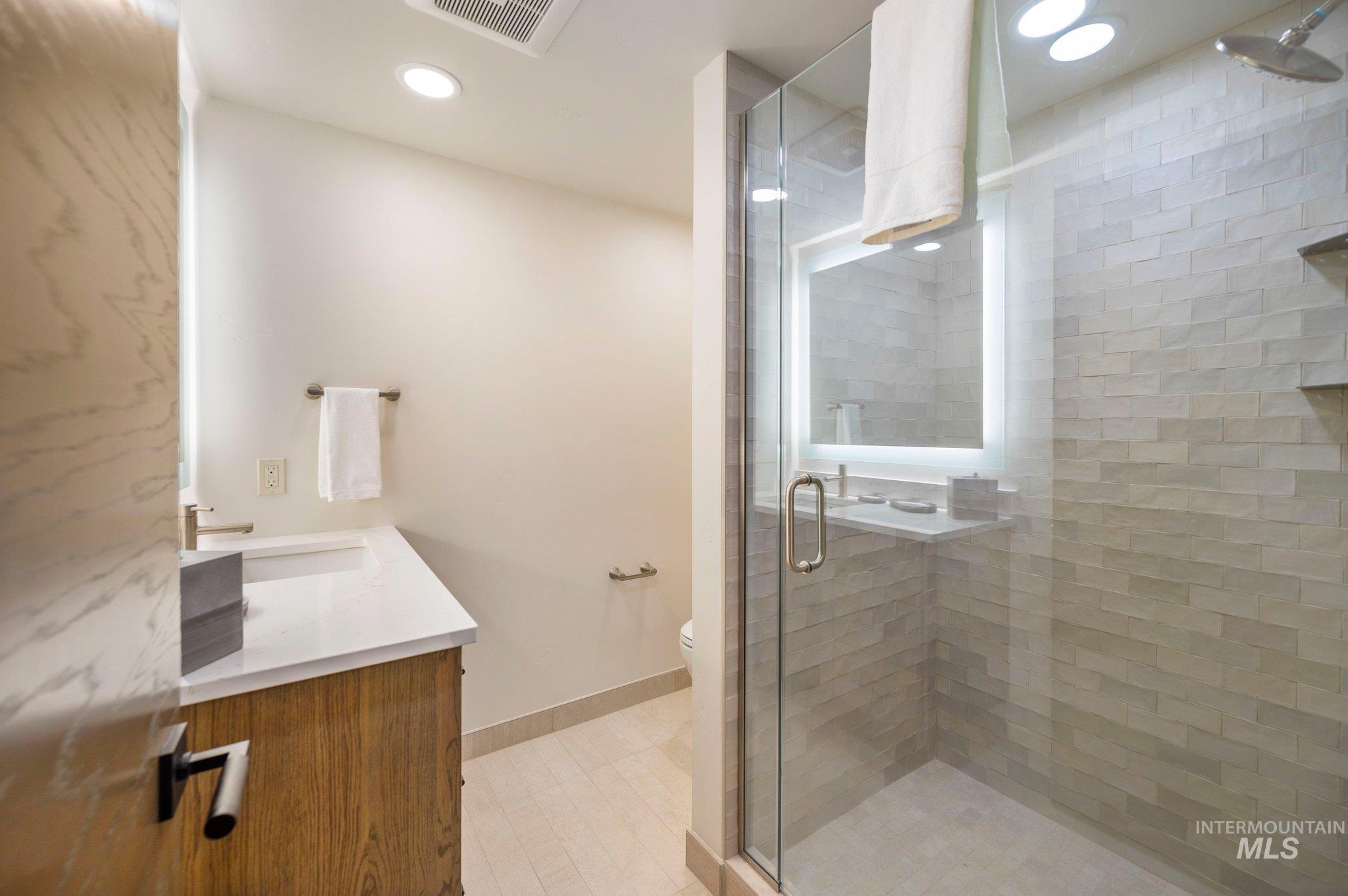 Full bathroom with vanity, a stall shower, and recessed lighting