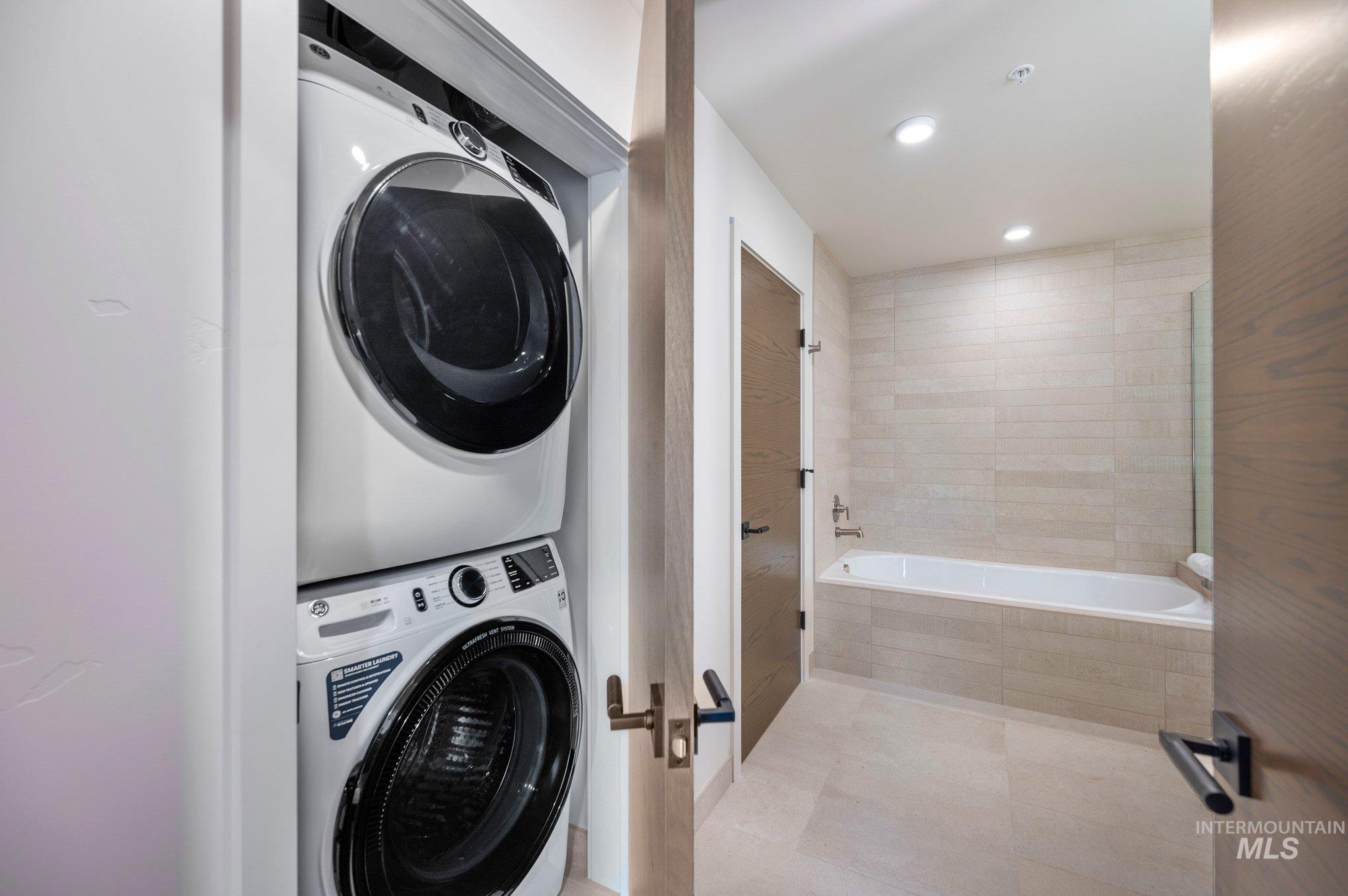Laundry room with stacked washer / drying machine, recessed lighting, and light tile patterned floors