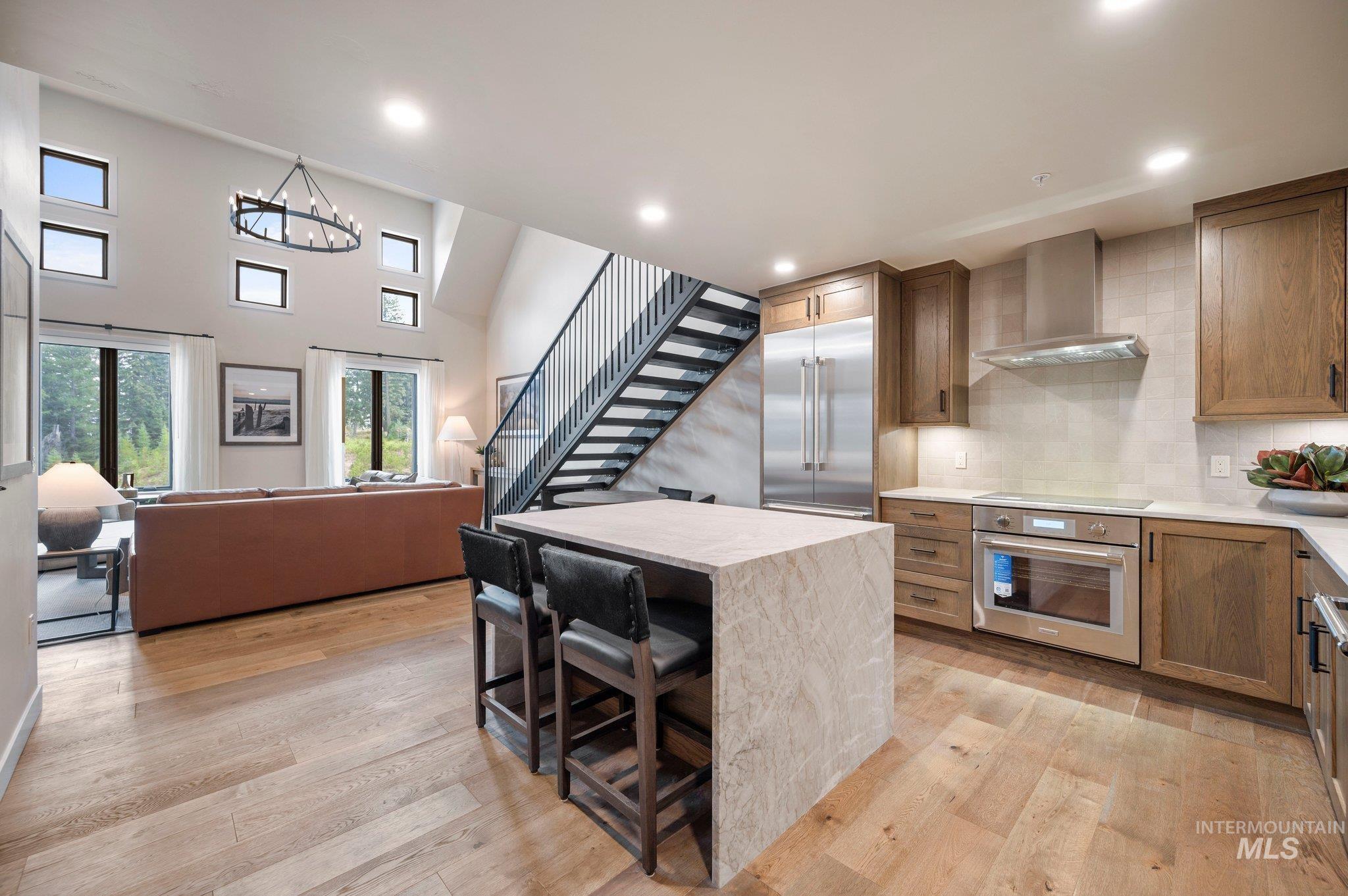 Kitchen featuring backsplash, appliances with stainless steel finishes, light wood-style floors, light stone countertops, and recessed lighting
