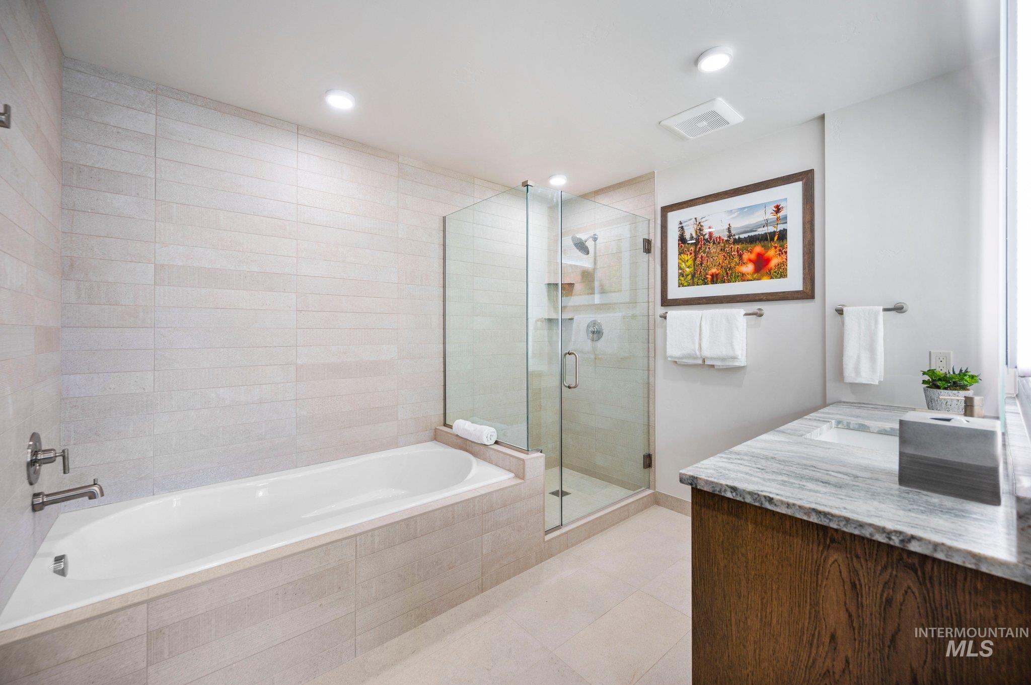 Bathroom featuring a shower stall, a bath, vanity, light tile patterned floors, and recessed lighting