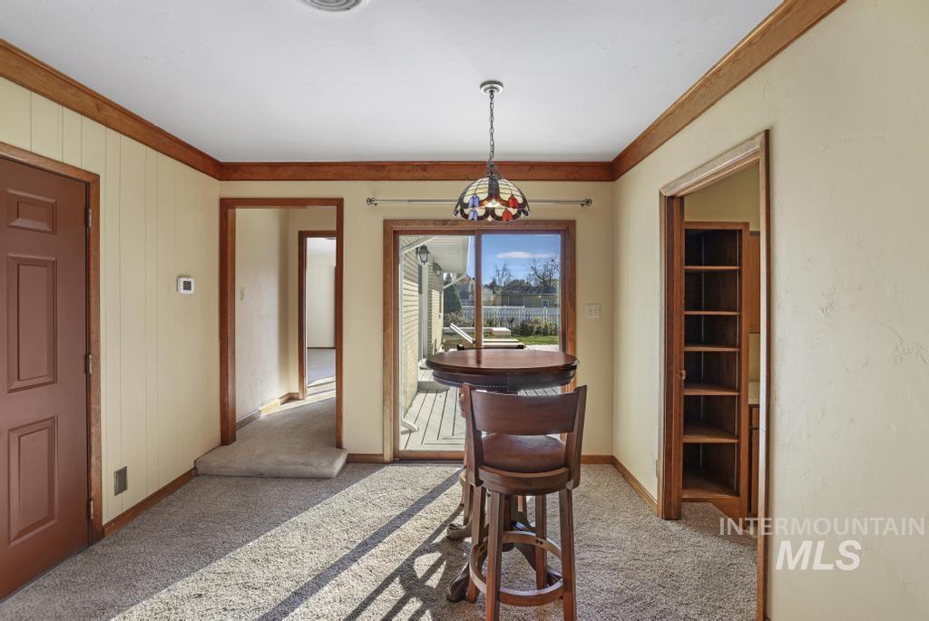 Dining space featuring light colored carpet and ornamental molding