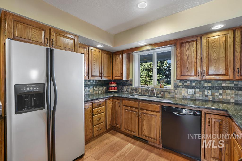 Kitchen featuring stainless steel fridge, brown cabinets, dishwasher, light wood-style floors, and recessed lighting