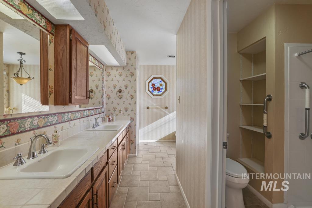 Full bath featuring double vanity and wallpapered walls