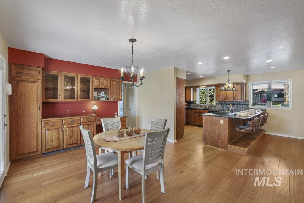 Dining room featuring light wood finished floors, a chandelier, recessed lighting, and a textured ceiling