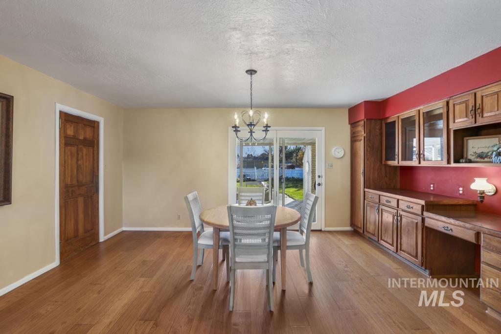 Dining area with a textured ceiling, light wood-style flooring, a chandelier, and built in study area