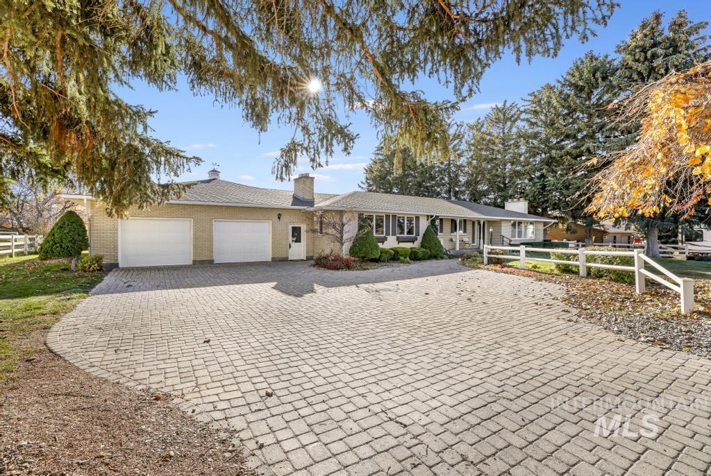 Single story home featuring an attached garage, decorative driveway, brick siding, and a chimney