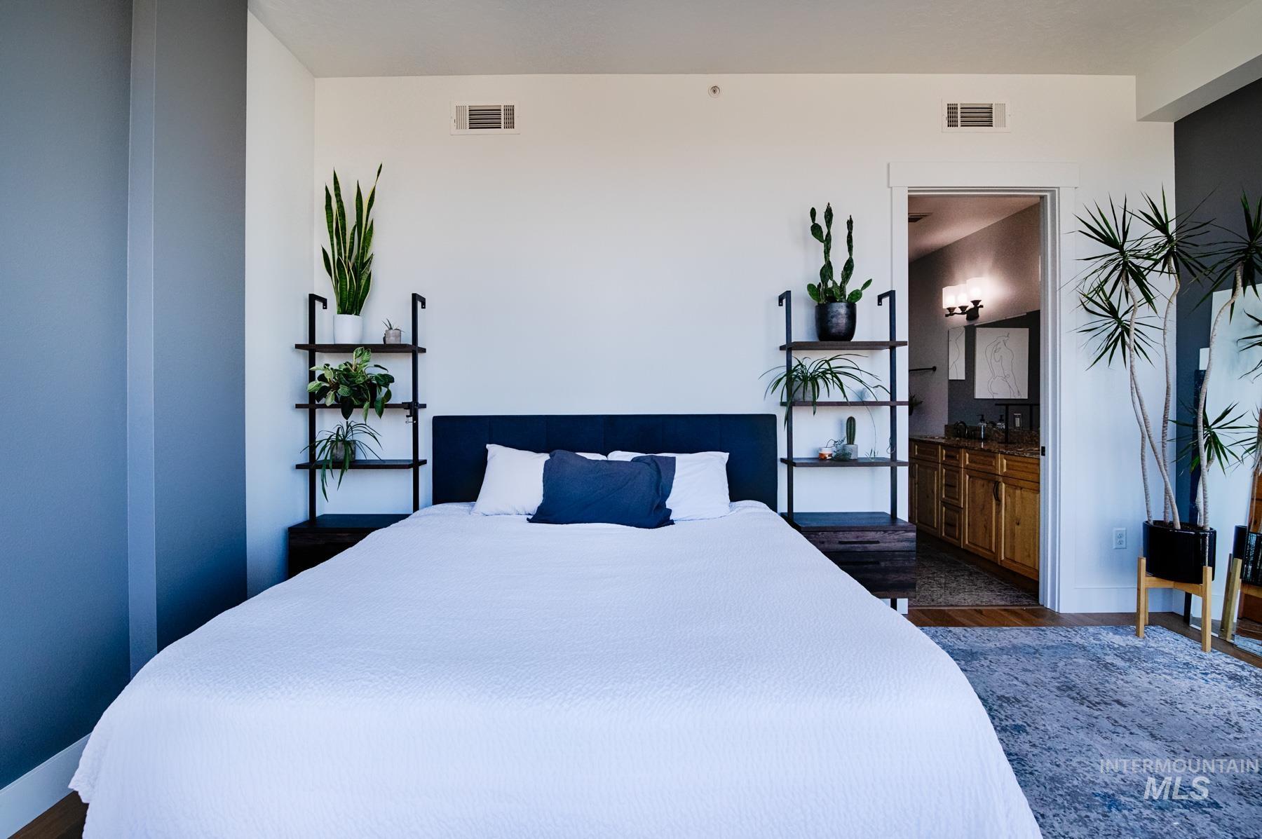 Bedroom with dark wood finished floors and connected bathroom
