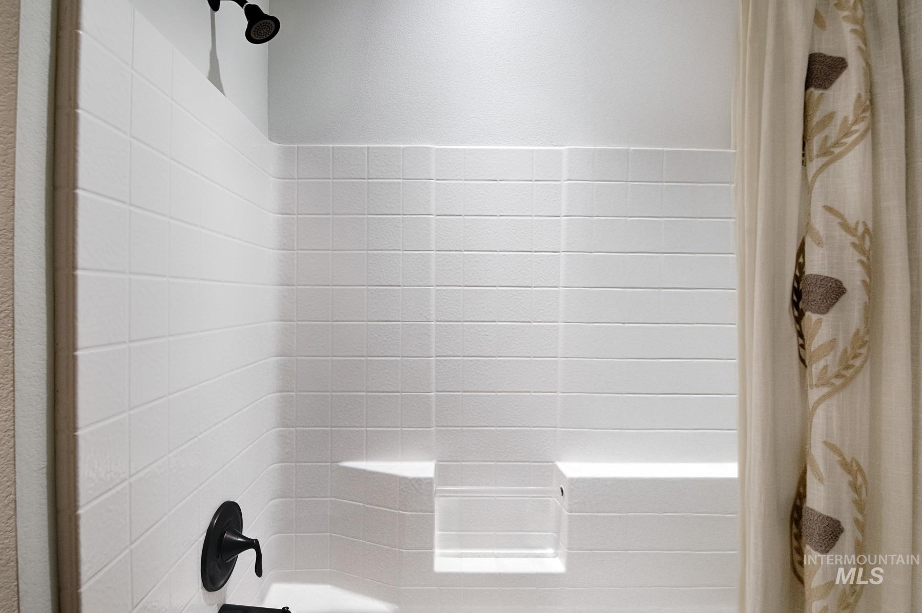 Bathroom view of shower / tub combo with curtain